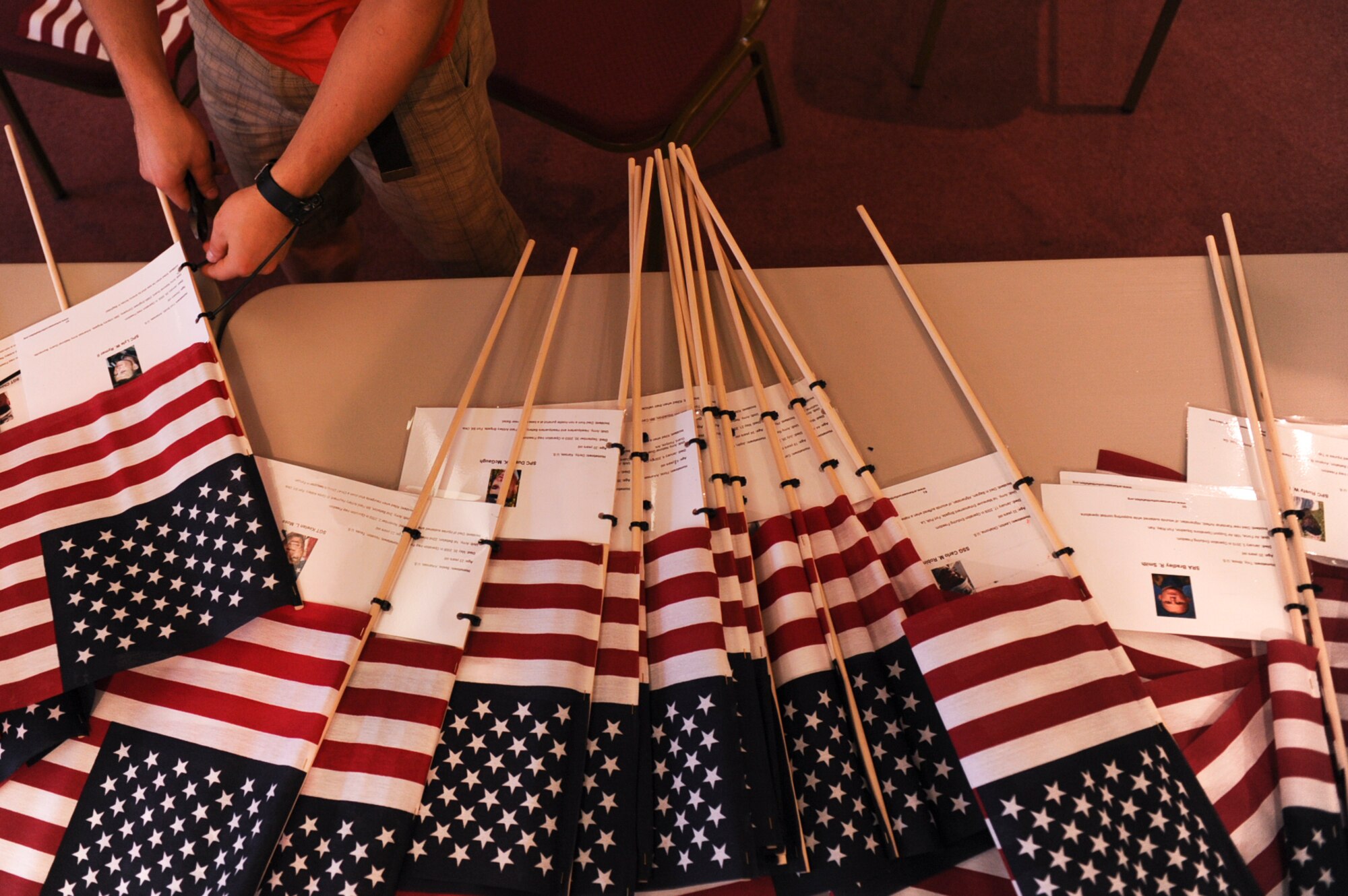 Bayr Lukomyansky, a 19th Medical Group pediatric clinic medical technician, places the biography of fallen Arkansan service members on American flags to be placed at every mile marker March 15, 2013, at Ozark, Ark. Participants placed 138 flags along Arkansas highway 64, from Ozark,  to Little Rock, Ark. (U.S. Air Force photo by Airman 1st Class Cliffton Dolezal)