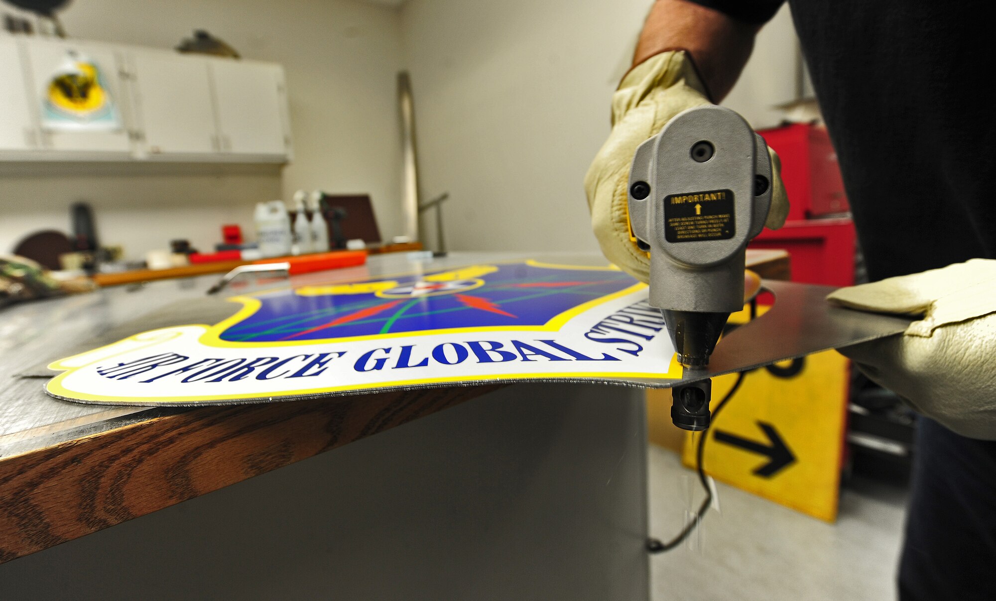 Bernard Jones, 509th Civil Engineer Squadron sign maker, uses a nibbler to cut away excess aluminum from a Global Strike Command insignia at Whiteman Air Force Base, Mo., March 11, 2013. MAJCOM signs help show visitors and newcomers the command’s ownership of the installation. (U.S. Air Force photo by Staff Sgt. Nick Wilson/Released) 