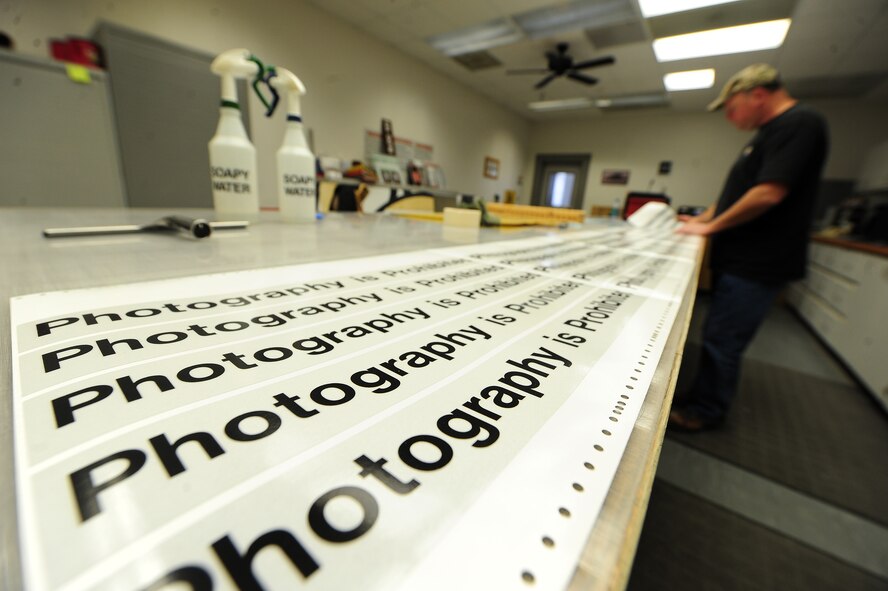 Bernard Jones, 509th Civil Engineer Squadron sign maker, weeds sign material and visually checks for flaws on a sign at Whiteman Air Force Base, Mo., March 11, 2013. The flaws Jones is checking for are errors in colors, spelling and other blemishes. (U.S. Air Force photo by Staff Sgt. Nick Wilson/Released)