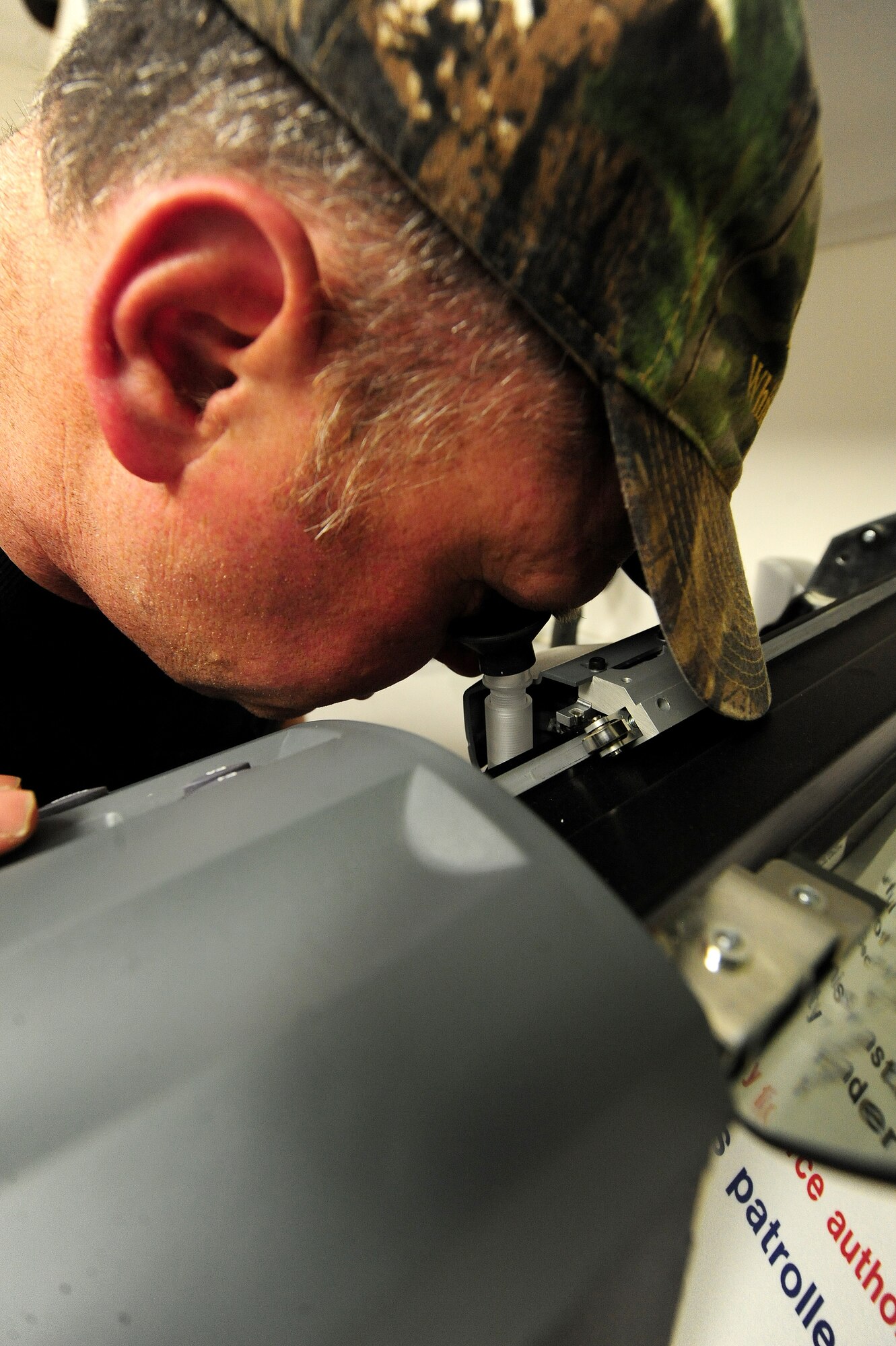 Bernard Jones, 509th Civil Engineer Squadron sign maker, uses the sight scope of a plotter machine to ensure the blade is properly lined up with the material being cut, March 11, 2013. The signs Jones creates are used for everything from office entryway signs to restricted area signs on the flightline. (U.S. Air Force photo by Staff Sgt. Nick Wilson/Released)