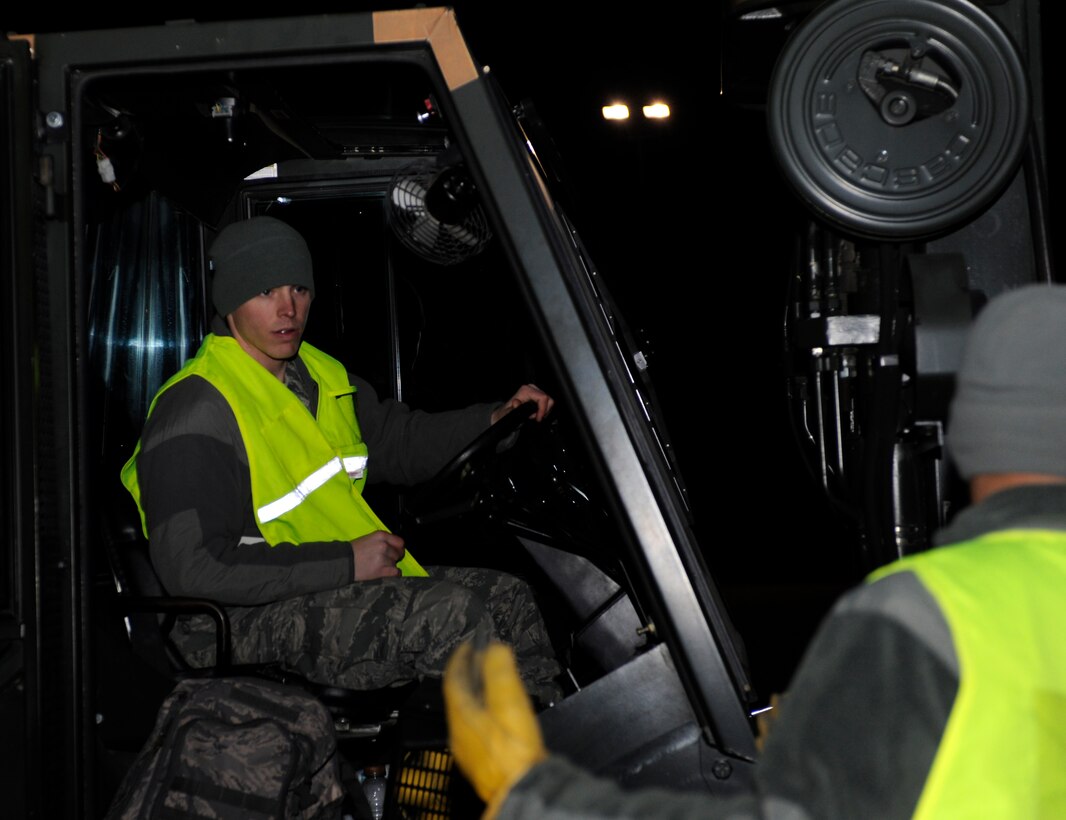 Senior Airman Josh Binfield (left), 28th Civil Engineer Squadron electrical systems technician, drives a cargo pallet while guided by Airman 1st Class Nikko Manga (right), 28th CES electrical systems technician, to a drop-off location outside the Pride Hangar during an operational readiness exercise on Ellsworth Air Force Base, S.D., March 19, 2013. Airmen from the 28th CES partnered with colleagues from the 28th Logistics Readiness Squadron to practice loading cargo during the ORE. (U.S. Air Force photo by Airman 1st Class Ashley J. Thum/Released)