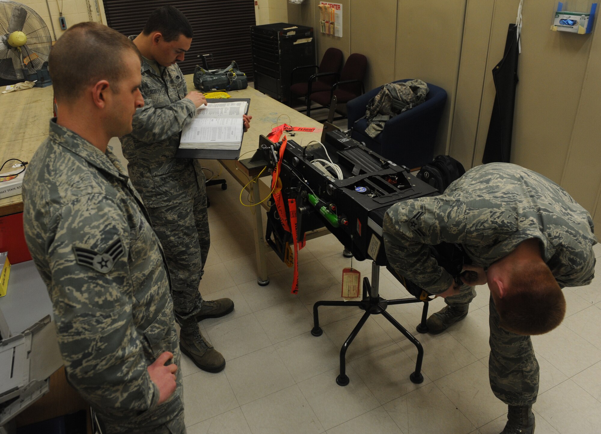 Senior Airman Patrick Hatcher, Airman 1st Class Matthew Roberts, and Airman 1st Class Christopher Amsel, 509th Maintenance Squadron egress systems journeymen, inspect a training ejection seat at Whiteman Air Force Base, Mo., March 19, 2013. Every 30 days, the B-2 Spirit cockpit seat must be inspected by someone with a 7-level training certification. (U.S. Air Force photo by Airman 1st Class Bryan Crane/Released)