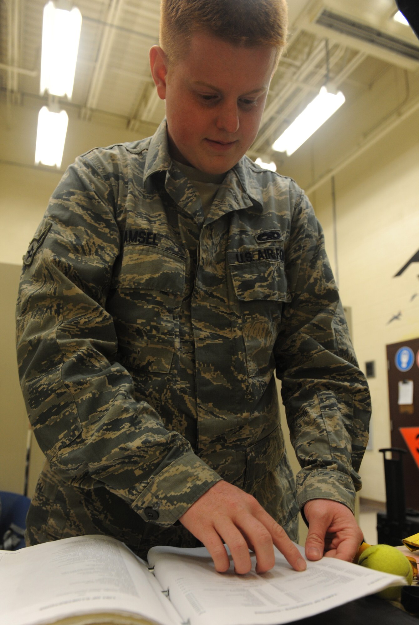 Airman 1st Class Christopher Amsel, 509th Maintenance Squadron egress systems journeyman, reviews a training manual while working on a training ejection seat at Whiteman Air Force Base, Mo., March 19, 2013. The egress shop consists of 18 Airmen who work in two shifts. (U.S. Air Force photo by Airman 1st Class Bryan Crane/Released)