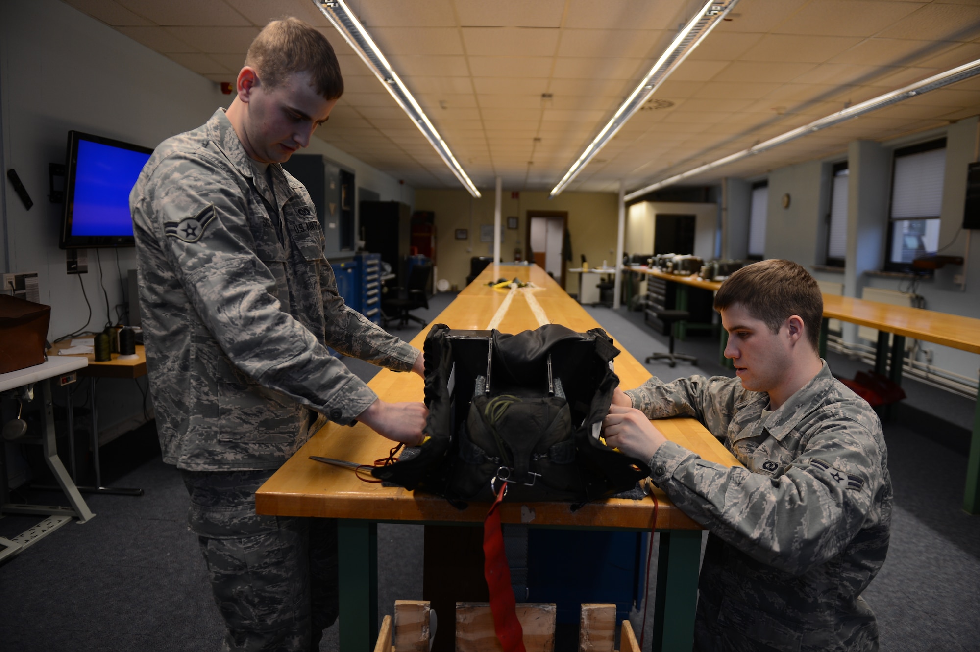 SPANGDAHLEM AIR BASE, Germany – U.S. Air Force Airman 1st Class Remington Murphy, 52nd Operations Support Squadron aircrew flight equipment technician from Richland, Wash., and Airman 1st Class Daniel Sisler, 52nd OSS aircrew flight equipment technician from Somerset, Wis., begin the final process to pack an advanced concept ejection seat March 20, 2013. The aircrew flight equipment shop inspects an average of three to five parachute riggings per week. (U.S. Air Force photo by Airman 1st Class Gustavo Castillo/Released)