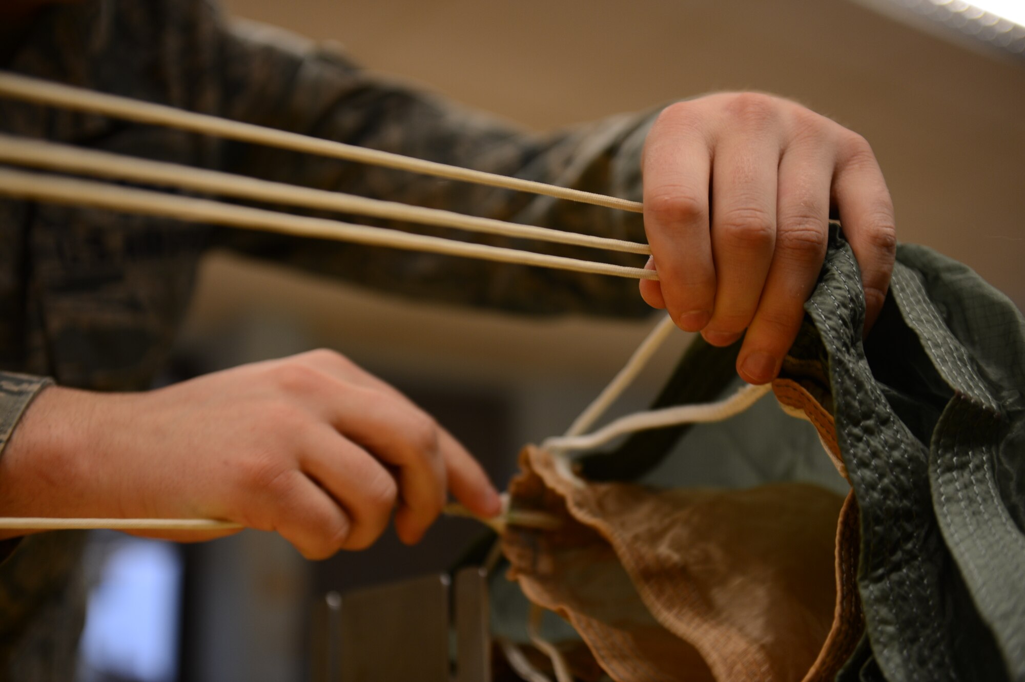 SPANGDAHLEM AIR BASE, Germany – U.S. Air Force Airman 1st Class Daniel Sisler, 52nd Operations Support Squadron aircrew flight equipment technician from Somerset, Wis., separates the cords on a parachute March 20. 2013. A visual inspection must be done every year to ensure the quality of the parachutes in case of emergency use. (U.S. Air Force photo by Airman 1st Class Gustavo Castillo/Released)