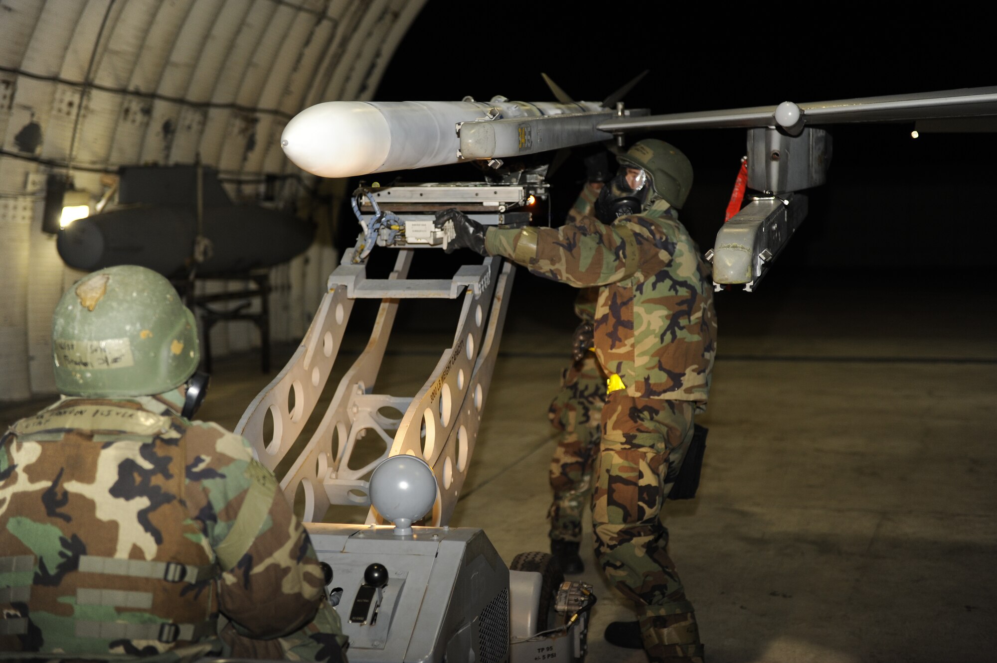 KUNSAN AIR BASE, Republic of Korea -- Staff Sgt. Joshua Chapman, 8th Maintenance Operations Squadron, middle, and Senior Airman Gregory Washington, 8th Maintenance Squadron, attach a missile onto an F-16 Fighting Falcon, as Senior Airman Brandon Oliver, 8th MOS, holds the missile steady with the bomb loader during exercise Beverly Midnight 13-2 at Kunsan Air Base, Republic of Korea, March 21, 2013. Maintenance personnel armed aircraft while in full Mission Oriented Protective Posture gear, due to the simulated contaminated environment. (U.S. Air Force photo by Senior Airman Marcus Morris/Released)