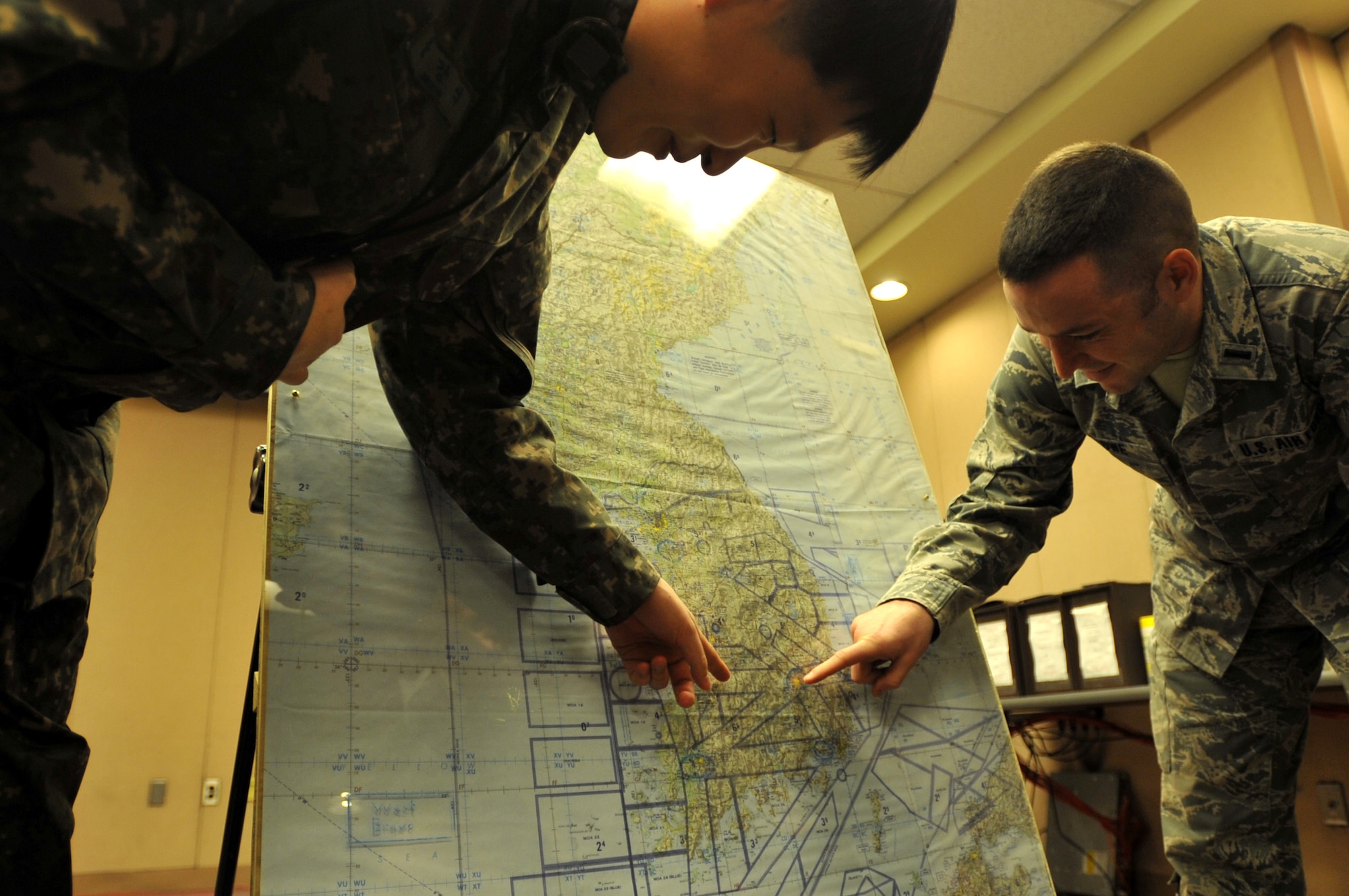 Republic of Korea Air Force Capt. Moon, Kang Sik, 7th Air Force white cell communications operator, and U.S. Air Force 1st Lt. Justin Lowe, 7th Air Force white cell force support liaison, discuss locations on a map during Exercise Key Resolve on Osan Air Base, Republic of Korea, March 21, 2013. Key Resolve is an annual combined and joint command post exercise that is executed under various scenarios with the purpose of honing the skills necessary to defend the Republic of Korea by improving ROK-U.S. combined forces’ operational capabilities, coordinating and executing the deployment of U.S. reinforcements, and maintaining ROK military combat capabilities. (U.S. Air Force photo/Airman 1st Class Hailey R. Davis)