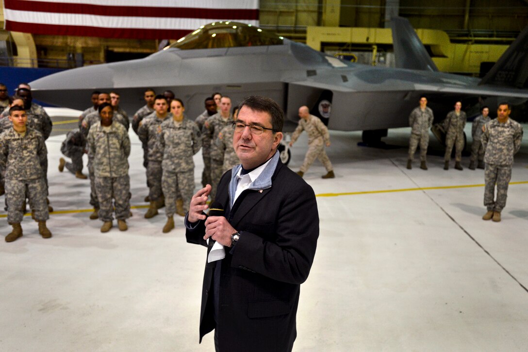 With an F22 fighter jet as a backdrop, Deputy Defense Secretary Ash Carter visits with troops on Joint Base Elmendorf-Richardson, Alaska, March 21, 2013, during a stop on his return trip from Asia. While there, Carter also looked over an F-22 fighter jet and a Stryker vehicle, and presented service members with commemorative coins.