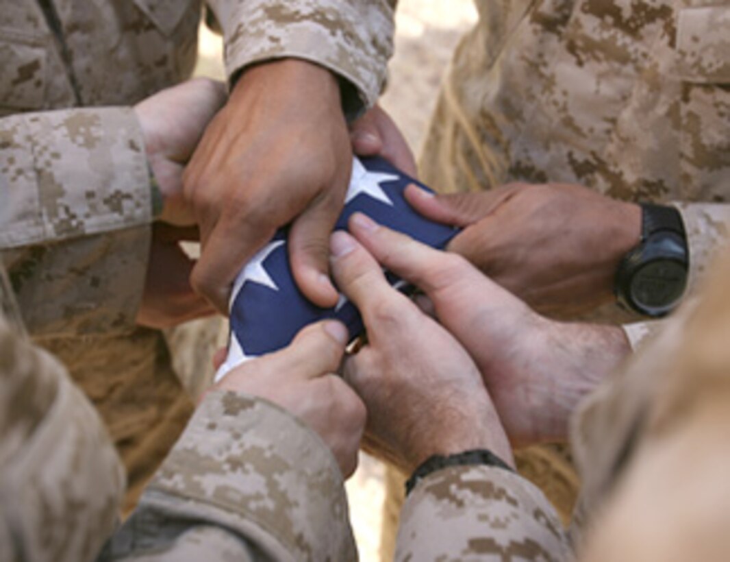 Marines fold a flag in honor of fallen comrades.