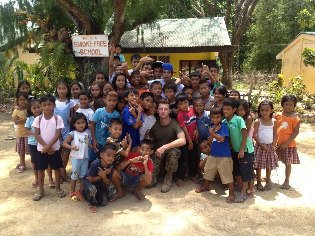 Cpl. Cameron T. Grant, a combat engineer with Bravo Company, 7th Engineer Support Battalion, 1st Marine Logistics Group, poses with children at an elementary school in Dumaguete, Philippines, while participating in Pacific Angel, March 3, 2013. Grant, 22, from Denver, helped rebuild a dilapidated school during the 10-day project.