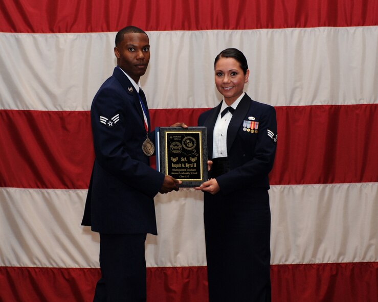 Senior Airman Jaquit Byrd, 2nd Maintenance Squadron, receives the Distinguished Graduate Award from Senior Airman Karina Reyes, 2nd Contracting Squadron, on behalf of the Air Force Sergeants Association during the Airman Leadership School Class 13-3 Graduation on Barksdale Air Force Base, La., March 21. (U.S. Air Force photo)