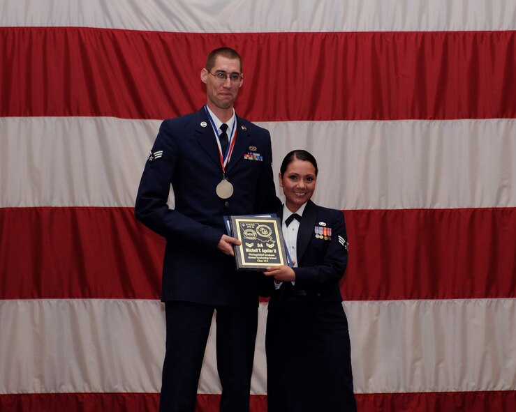 Senior Airman Mitchell Aguilar, 2nd Aircraft Maintenance Squadron, receives the Distinguished Graduate Award from Senior Airman Karina Reyes, 2nd Contracting Squadron, on behalf of the Air Force Sergeants Association during the Airman Leadership School Class 13-3 Graduation on Barksdale Air Force Base, La., March 21. (U.S. Air Force photo)