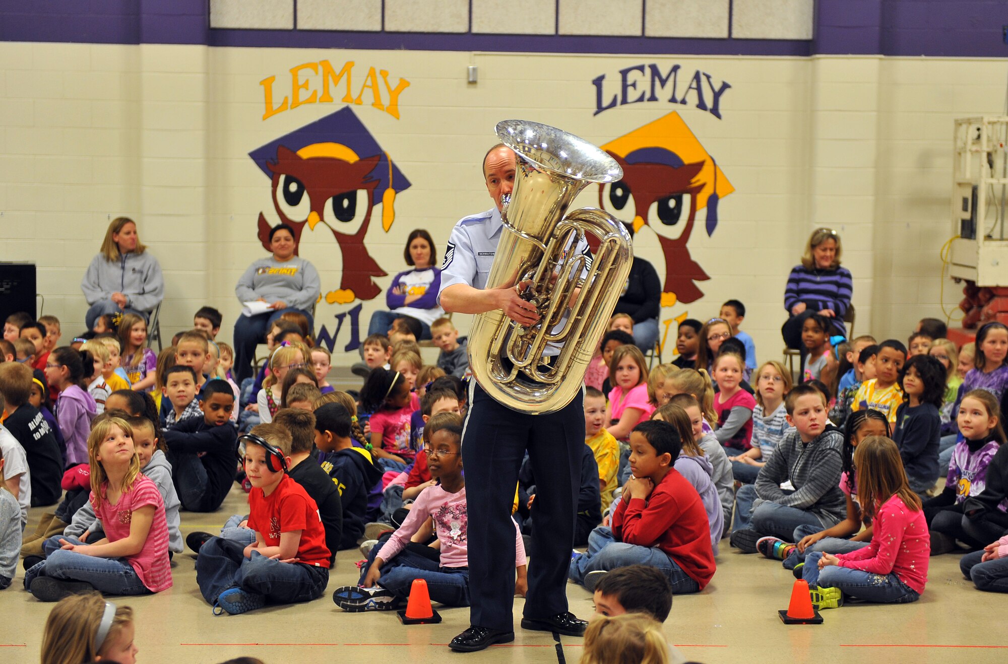 U.S. Air Force Master Sgt. Alex Serwatowski, a tuba player with the Heartland of America Band, entertains children of LeMay Elementary School on March 21, Offutt Air Force Base, Neb.  The Offutt Brass Ensemble has been performing at several metro area schools with an around-the-world medley of different composers to include both the Star Wars and Spiderman theme music.  (U.S. Air Force photo by Josh Plueger/Released)