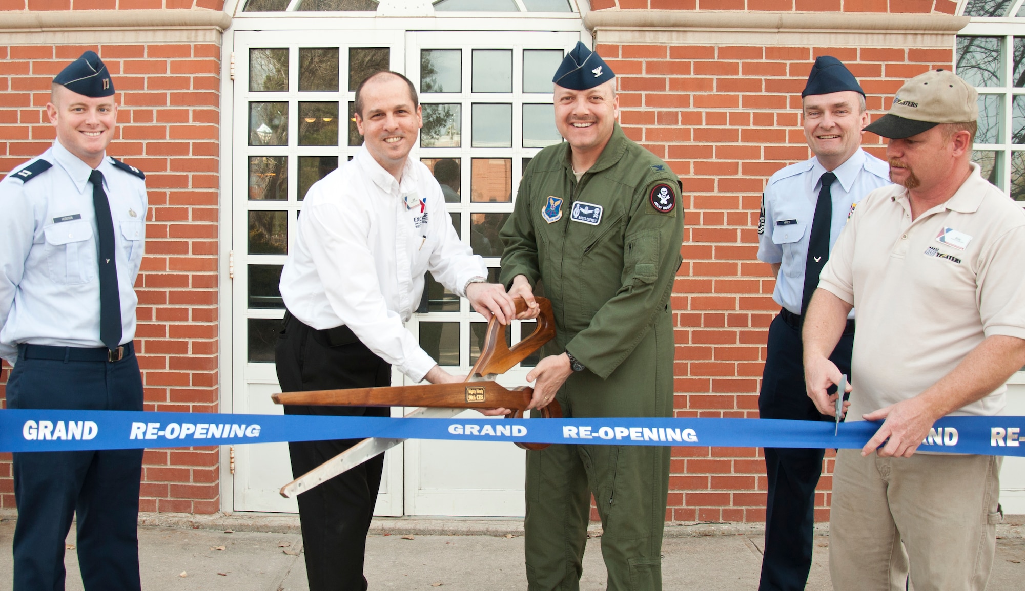 Jeff Hyatt, F. E. Warren Army and Air Force Exchange Service manager, and Col. Christopher Coffelt, 90th Missile Wing commander, pose ceremonial scissors at the F. E. Warren Base Theater grand re-opening ribbon cutting March 15. (U.S. Air Force photo by Airman 1st Class Jason Wiese)