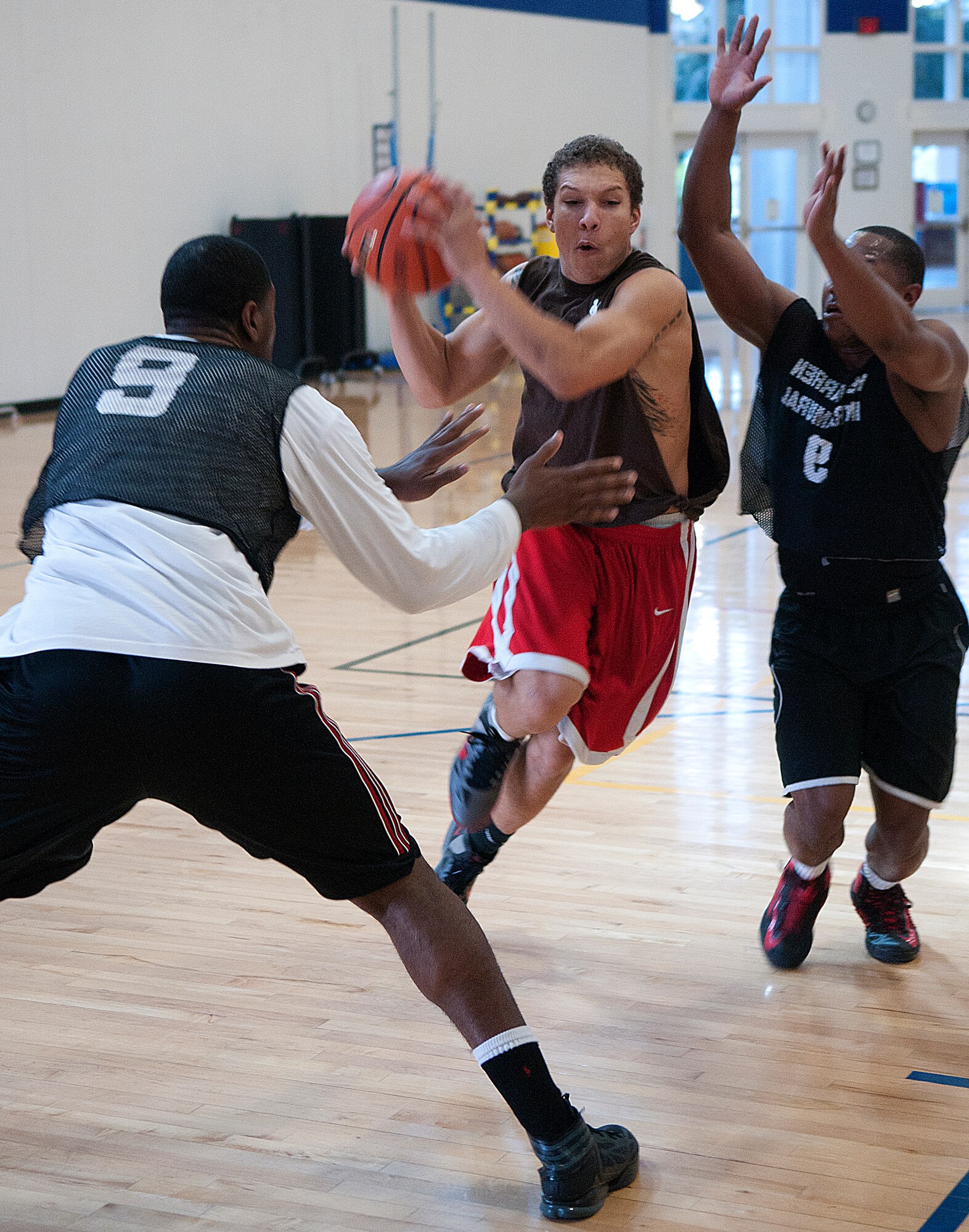 Deondré Davis of team Us threads his way through Uptown’s William Shelby and A.J. Brannon during the first of three games they played against each other in the Freedom Hall Fitness Center’s 3-on-3 basketball tournament March 15. Us went on to win this game 12-11, along with the final game to take the double-elimination tournament. (U.S. Air Force photo by R.J. Oriez)