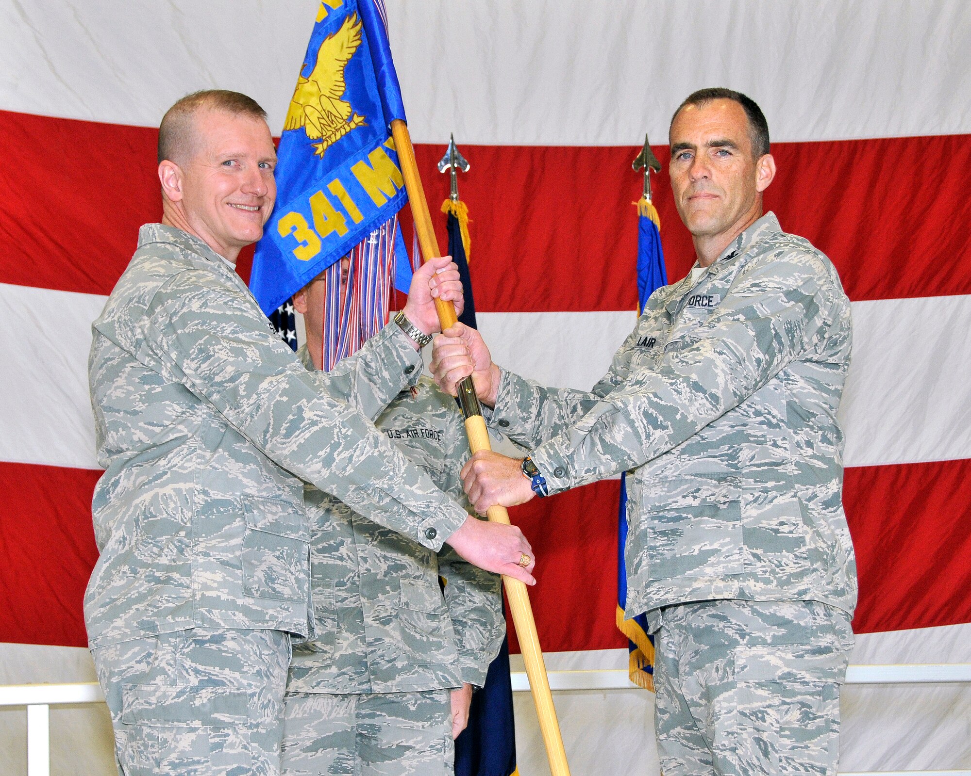 Col. David Lair, right, accepts command of the 341st Maintenance Group from Col. Robert Stanley, 341st Missile Wing commander, March 15 in the 3-Bay Hangar.  Chief Master Sgt. Michael Whittaker, 341st Maintenance Operations Squadron member, background, looks on.  (U.S. Air Force photo/John Turner)