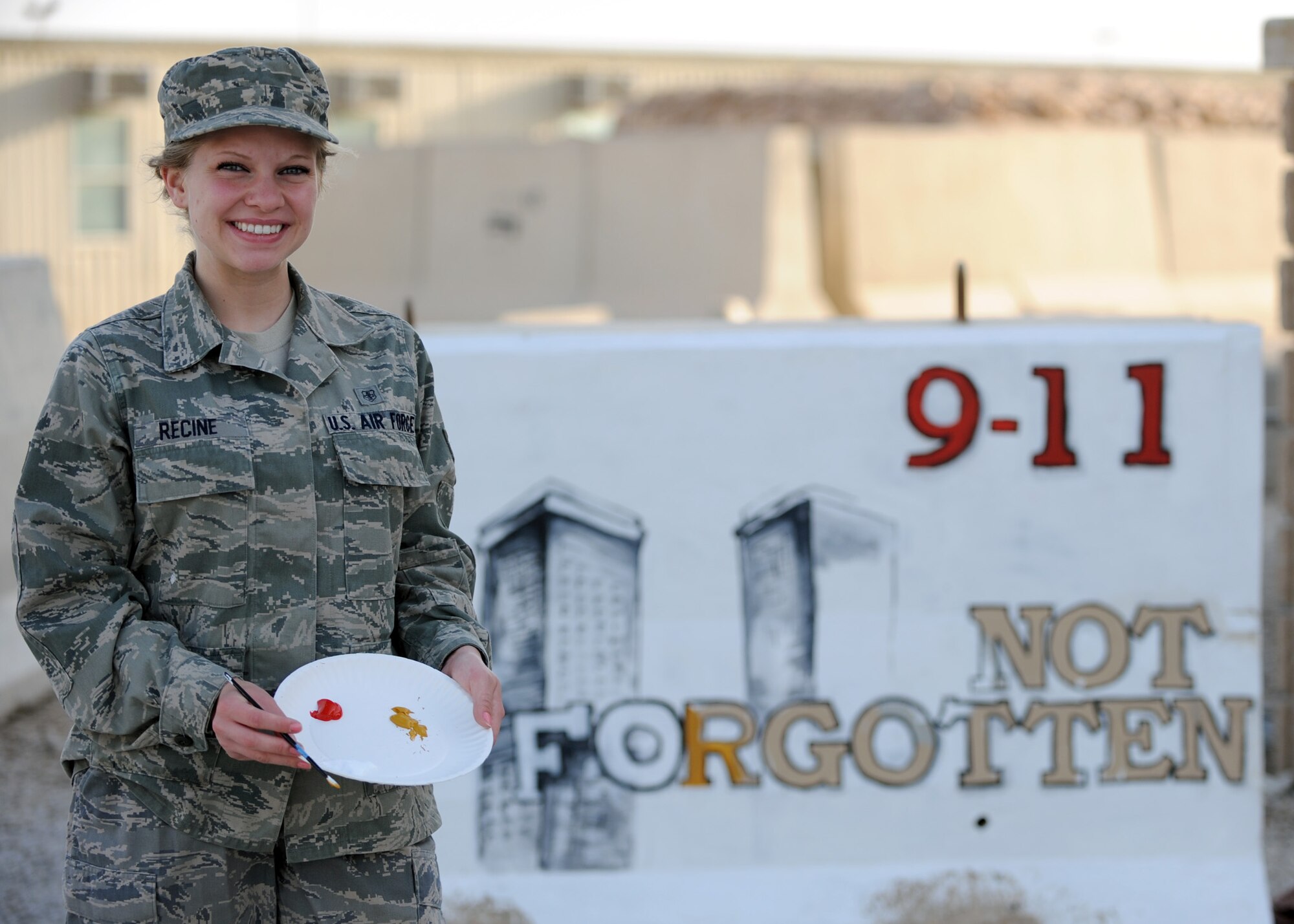 SOUTHWEST ASIA – Senior Airman Adrianna Recine, 379th Expeditionary Medical Group laboratory technician, volunteers her time to refurbish the 9/11 barrier memorial here, March 21.  Rising 6, a group dedicated to enlisted service members in the pay grades of E-1 through E-6, had adopted the memorial and asked for a volunteer to refurbish it. (U.S. Air Force photo/Senior Airman Joel Mease)