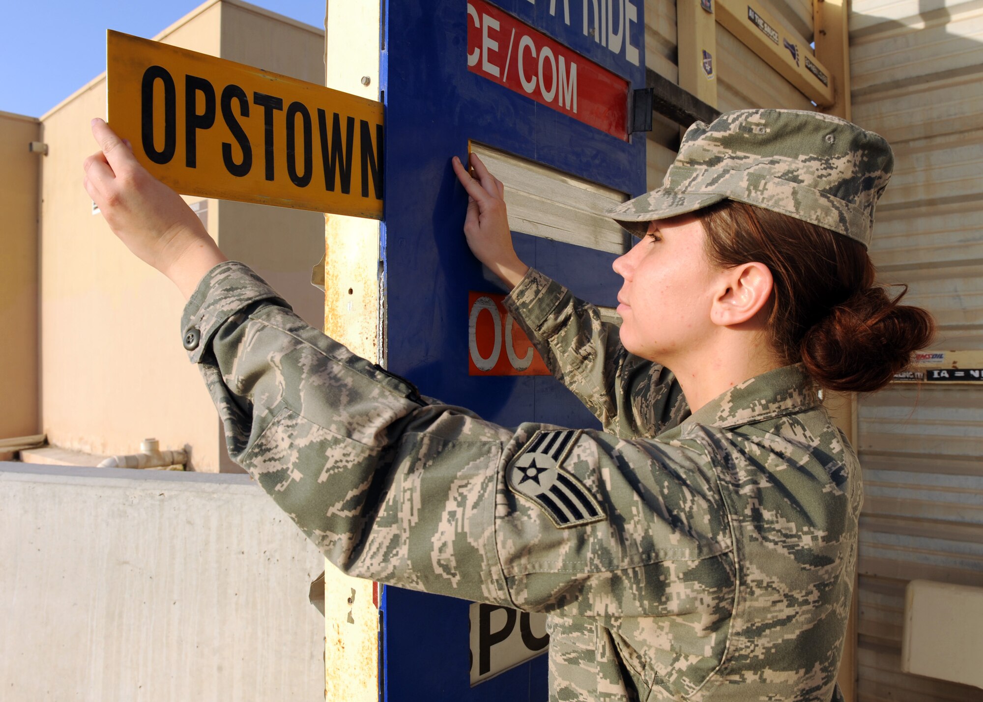 SOUTHWEST ASIA - Senior Airman Joy Bodiford, 379th Expeditionary Medical Group medical pharmacy technician, slides a request to be taken to the operational side of the installation at a bus stop in the Coalition Compound, March 21. By giving a service member who requests a ride, you can save him or her nearly half an hour on the journey. (U.S. Air Force photo/Senior Airman Joel Mease)