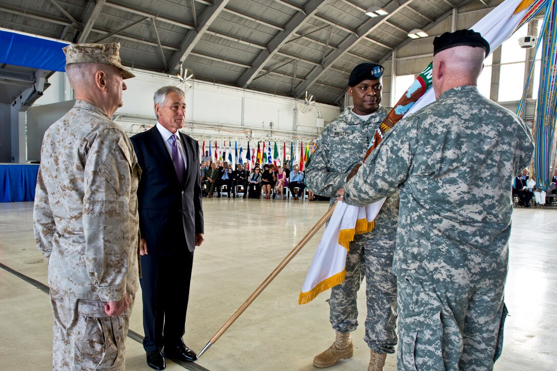 Defense Secretary Chuck Hagel stands as Army Gen. Lloyd J. Austin III holds the the U.S. Central Command colors after Marine Corps Gen. James N. Mattis, left, passed the command to Austin during the change-of-command ceremony on MacDill Air Force Base in Tampa, Fla., March 22, 2013.