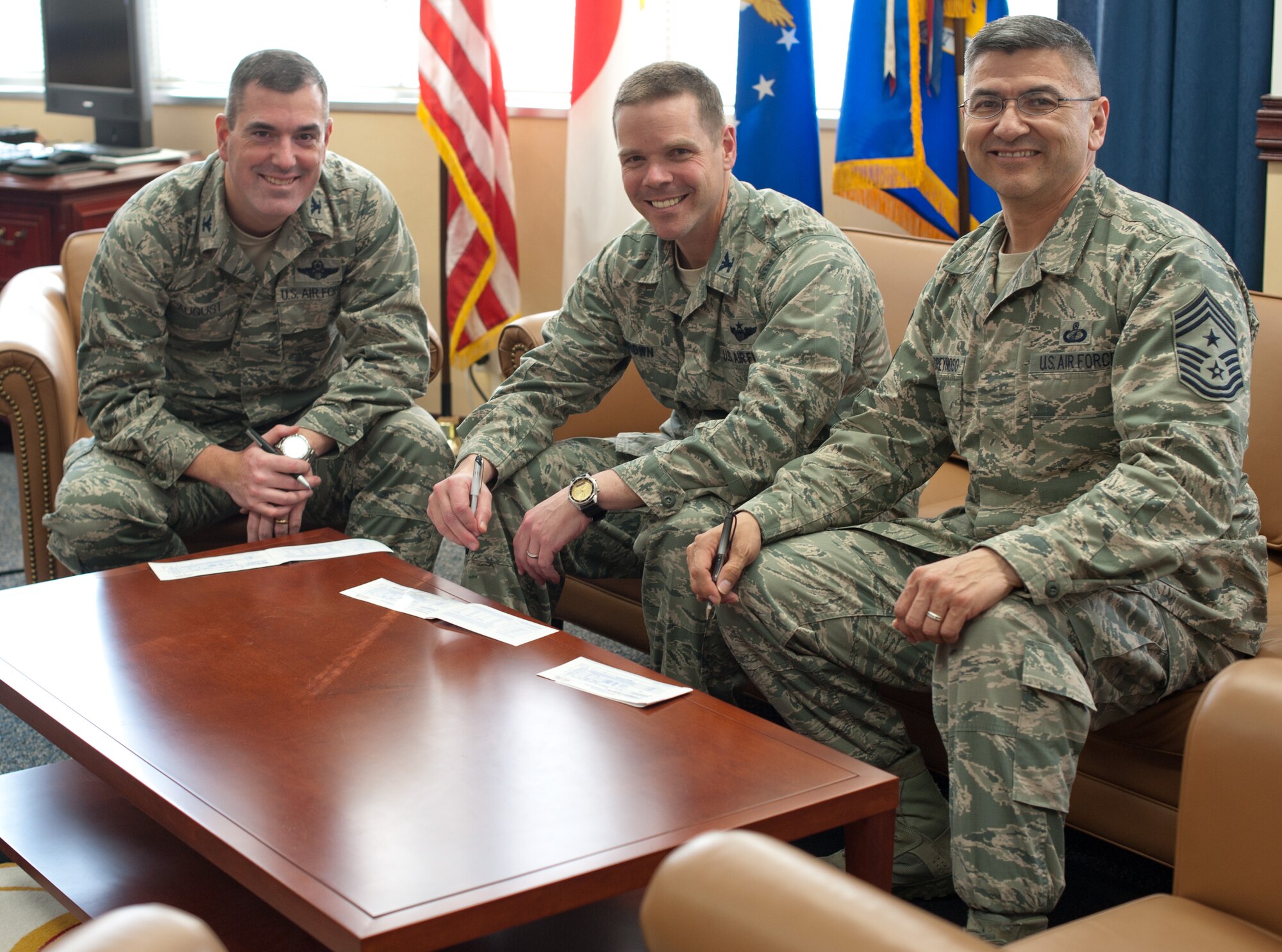 YOKOTA AIR BASE, Japan –Col. Mark August, 374th Airlift Wing commander, Col. Charles Brown vice wing commander, and Command Chief Master Sgt. Manuel Roblesreynoso, wing command chief, kickoff Yokota’s Air Force Assistance Fund campaign with their contributions March 21, 2013 at Yokota Air Base, Japan. (U.S. Air Force photo by Airman 1st Class Soo C. Kim)