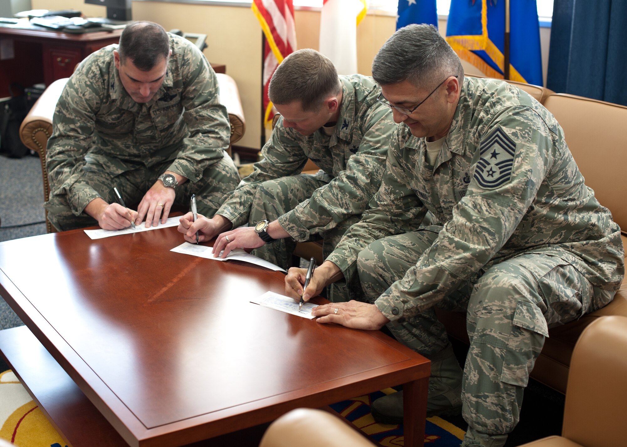 YOKOTA AIR BASE, Japan – Col. Mark August 374th Airlift Wing commander, Col. Charles Brown vice wing commander, and Command Chief Master Sgt. Manuel Roblesreynoso wing command chief, make the first contribution to the 2013 Air Force Assistance Fund March 21, 2013.  The AFAF campaign provides assistance for Airmen in need.  (U.S. Air Force photo by Airman 1st Class Soo C. Kim)