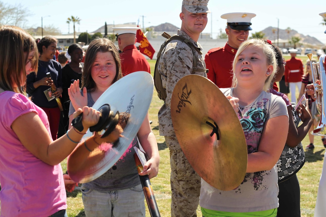 Evie Cox, 10, Kaitlynn Woody, 11, and Allison O’Brien, 11, students from Palm Vista Elementary School meet Marines from the United States Marine Corps Drum and Bugle Corps at the Combat Center’s Lance Cpl. Torrey L. Gray Field March 12, after a performance by the Marine Corps’ Battle Color Detachment. 