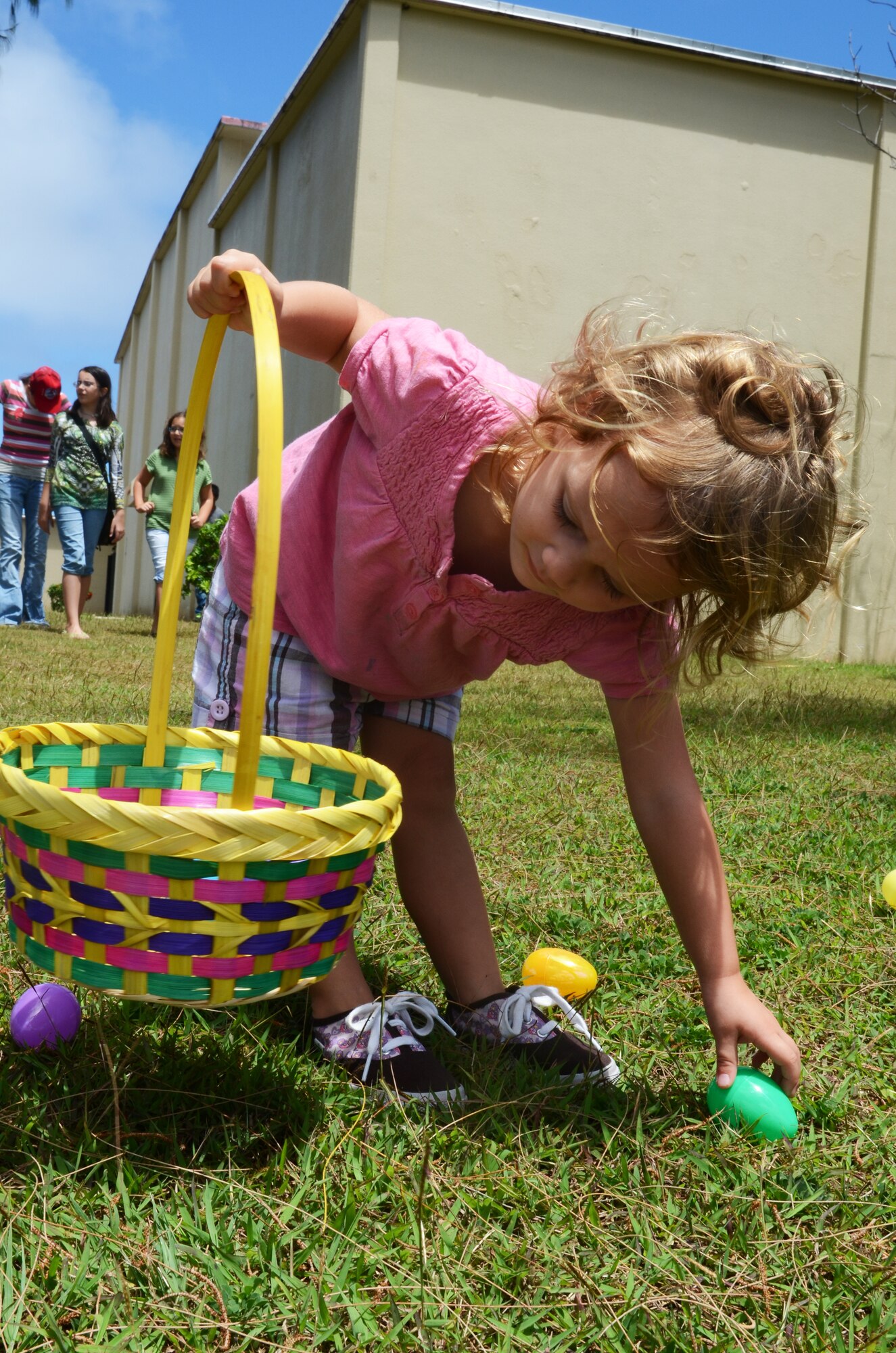 A child of a 554th RED HORSE Squadron service member gathers plastic eggs during the 554th RED HORSE Squadron Egg-stravaganza on Andersen Air Force, Guam, March 23, 2013. The squadron function was a combined information fair, potluck lunch and children’s Easter egg hunt planned by the unit’s spouses to help families of deployed military members celebrate the season and expose them to many of the base’s support programs. (U.S. Air Force photo by Senior Airman Benjamin Wiseman/Released)