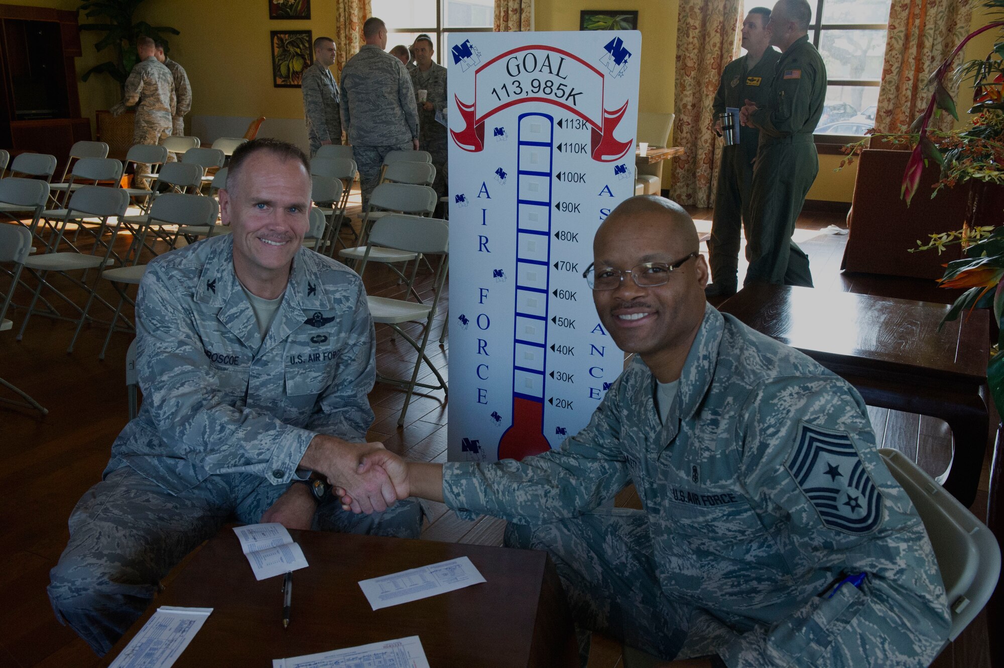 Col. John Roscoe, 15th Wing commander, and Chief Master Sgt. Leslie Bramlett, 15 WG command chief, congratulate one another after completing their Air Force Assistance Fund donation forms during the 2013 campaign kick-off in the Ka Makani Community Center at Joint Base Pearl Harbor-Hickam, Hawaii, on March 25, 2013. This year’s campaign will run from March 25-May 3. This year, the base goal is 100 percent contact and $113, 985 raised. (U.S. Air Force photo/Staff Sgt. Terri Paden)
