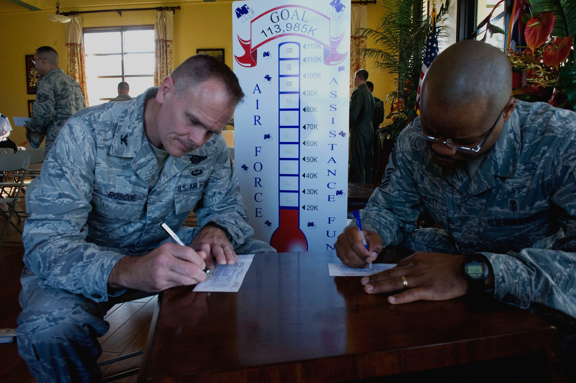 Col. John Roscoe, 15th Wing commander, and Chief Master Sgt. Leslie Bramlett, 15 WG command chief, fill out Air Force Assistance Fund donation forms during the 2013 campaign kick-off in the Ka Makani Community Center at Joint Base Pearl Harbor-Hickam, Hawaii, on March 25, 2013. Donations collected during the annual fundraiser directly support Air Force charities, including the Air Force Enlisted Village, the Air Force Aid Society, Air Force Villages Charitable Foundation and the Lemay Foundation. These organizations help Air Force people with aid in an emergency, with educational needs, or to have a secure retirement home for widows or widowers of Air Force members in need of financial assistance. (U.S. Air Force photo/Staff Sgt. Terri Paden)