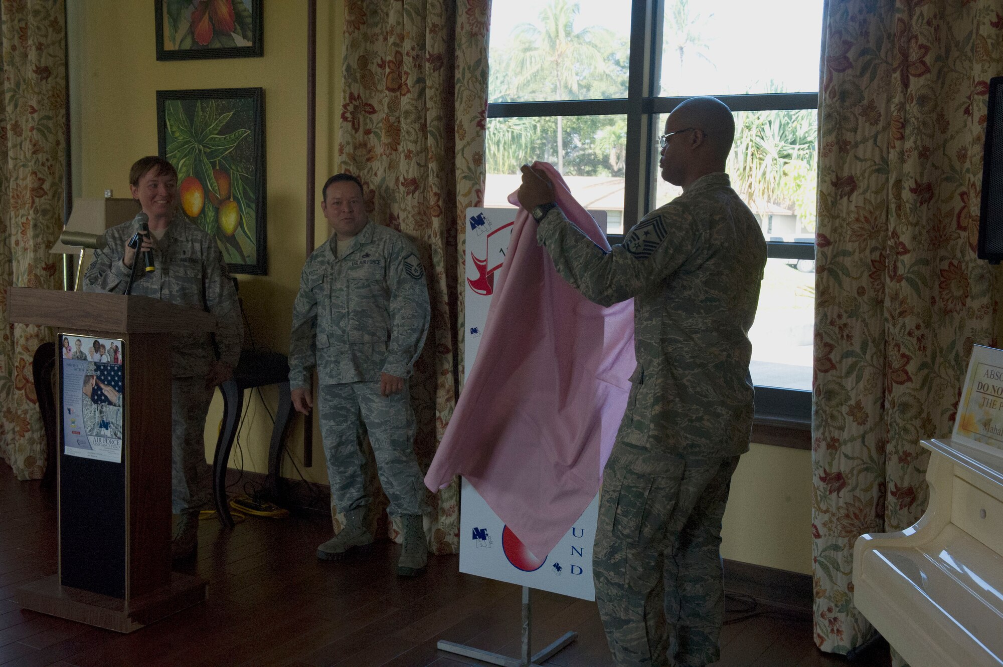 Senior Master Sgt. Michelle Rootes, 2013 Air Force Assistance Fund Installation Project Officer, (Far left) and Master Sgt. Jose Montoya, also a 2013 AFAF IPO, look on as Chief Master Sgt. Leslie Bramlett, 15th Wing command chief, unveils the wing’s AFAF donation goal in the Ka Makani Community Center at Joint Base Pearl Harbor-Hickam, Hawaii, on March 25, 2013. The AFAF was established to provide an annual effort to raise funds for the charitable affiliates that support the Air Force family to include active duty members, retirees, reservists, guardsmen and their dependents, including surviving spouses. (U.S. Air Force photo/Staff Sgt. Terri Paden)