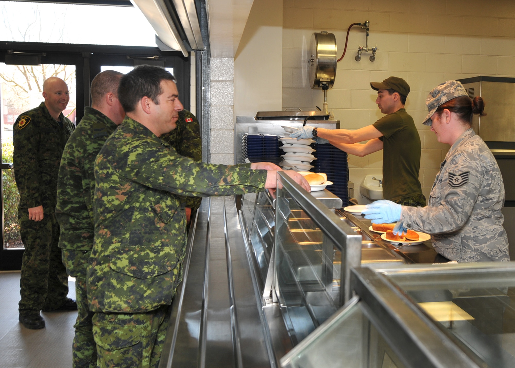 NEW LONDON, N.C.  – Army Master Corporal David Payette, a chef and member of the Royal Air Force 3 Wing Construction Engineers Canadian Forces from Bagotville, Quebec, and Tech. Sgt. Amanda Amoroso, 263rd Combat Communication Squadron serve breakfast to Canadian service members participating in the Deployment for Training Program. This two week program is an exchange agreement between the Royal Canadian Air Force and the United States Air National Guard. It was hosted In March 2013 by the 145th Civil Engineering Squadron at the North Carolina Air National Guard Regional Training Site in New London, N.C.  (National Guard Photo by Tech. Sgt. Patricia Findley, 145th Public Affairs) 