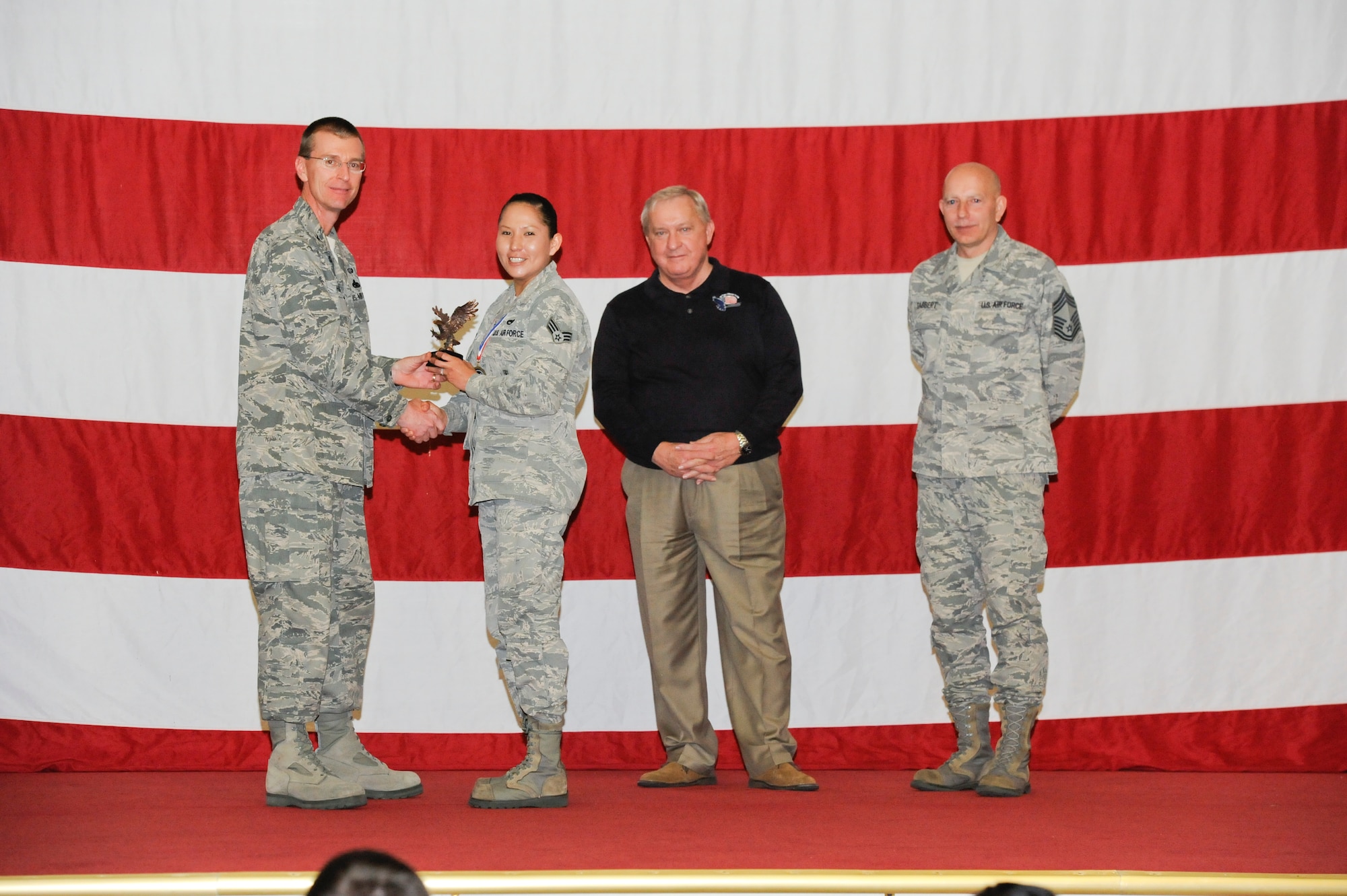 Senior Airman Monica Sathern, 43rd Aircraft Maintenance Unit, receives the award for the Staff Professional of the Year in the Airman category from Col. Curtis Hafer, 325th Maintenance Group commander, and Chief Master Sgt. Terry Gabbert, 325th MXG superintendent, and retired ninth Chief Master Sergeant of the Air Force, Chief Master Sgt. James Binnicker, during the 2012 Maintenance and Staff Professionals of the Year banquet in Hangar 1 March 15. The MPOY banquet recognizes the achievements of the maintenance group and honors maintenance professionals each year. (U.S. Air Force photo by Chris Cokeing)