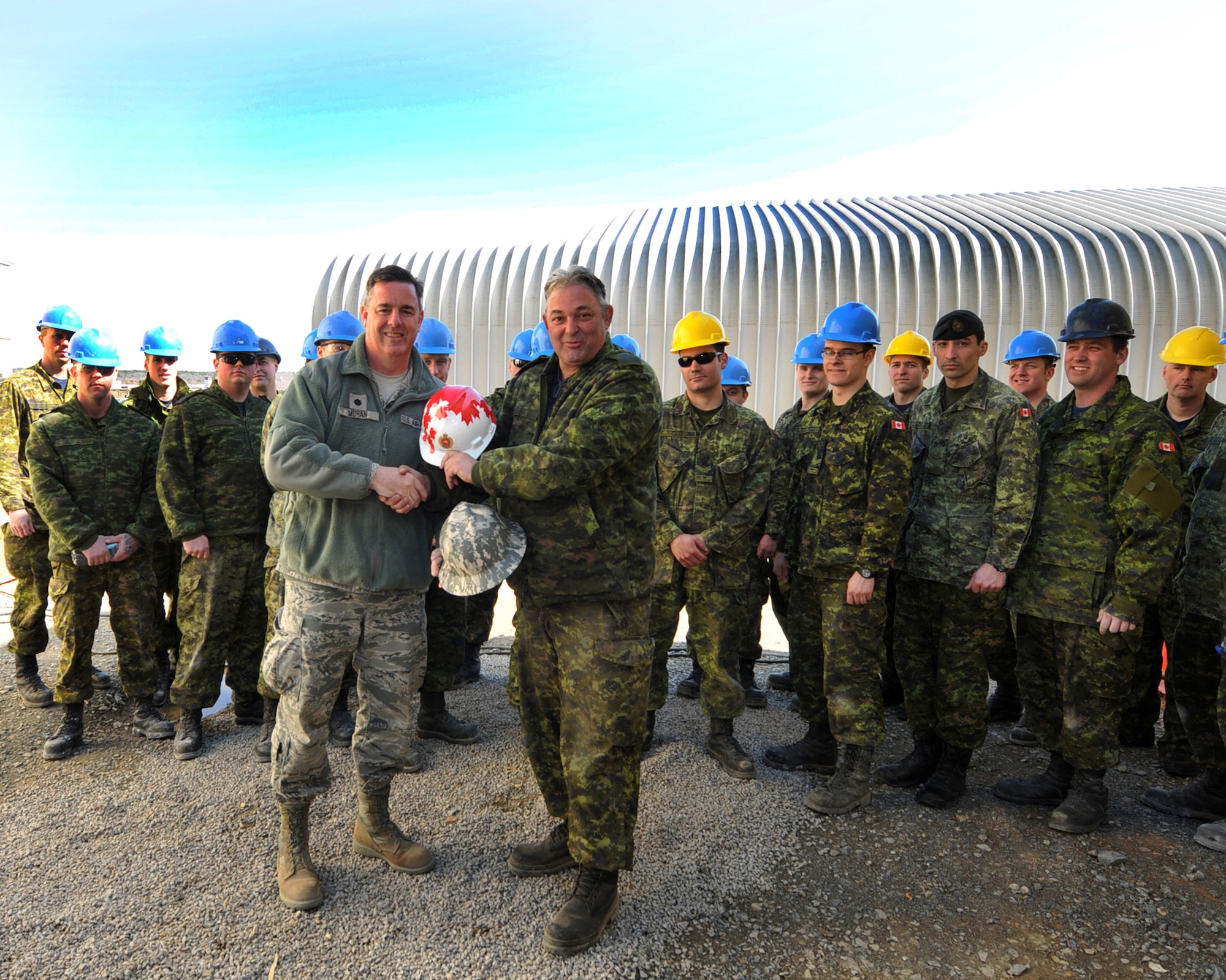 NEW LONDON, N.C.  – Lt. Col. Timothy Moran, Deputy Commander, 145th Engineer Squadron swaps construction helmets with Master Warrant Officer Martin Cloutier, Royal Air Force 3 Wing Construction Engineers Canadian Forces from Bagotville, Quebec. Cloutier is one of 26 engineers participating in a two week Deployment for Training Program, an exchange agreement between the Royal Canadian Air Force and the United States Air National Guard hosted by 145th Civil Engineering Squadron at the North Carolina Air National Guard Regional Training Site in New London, N.C.  (National Guard Photo by Tech. Sgt. Patricia Findley, 145th Public Affairs) 

