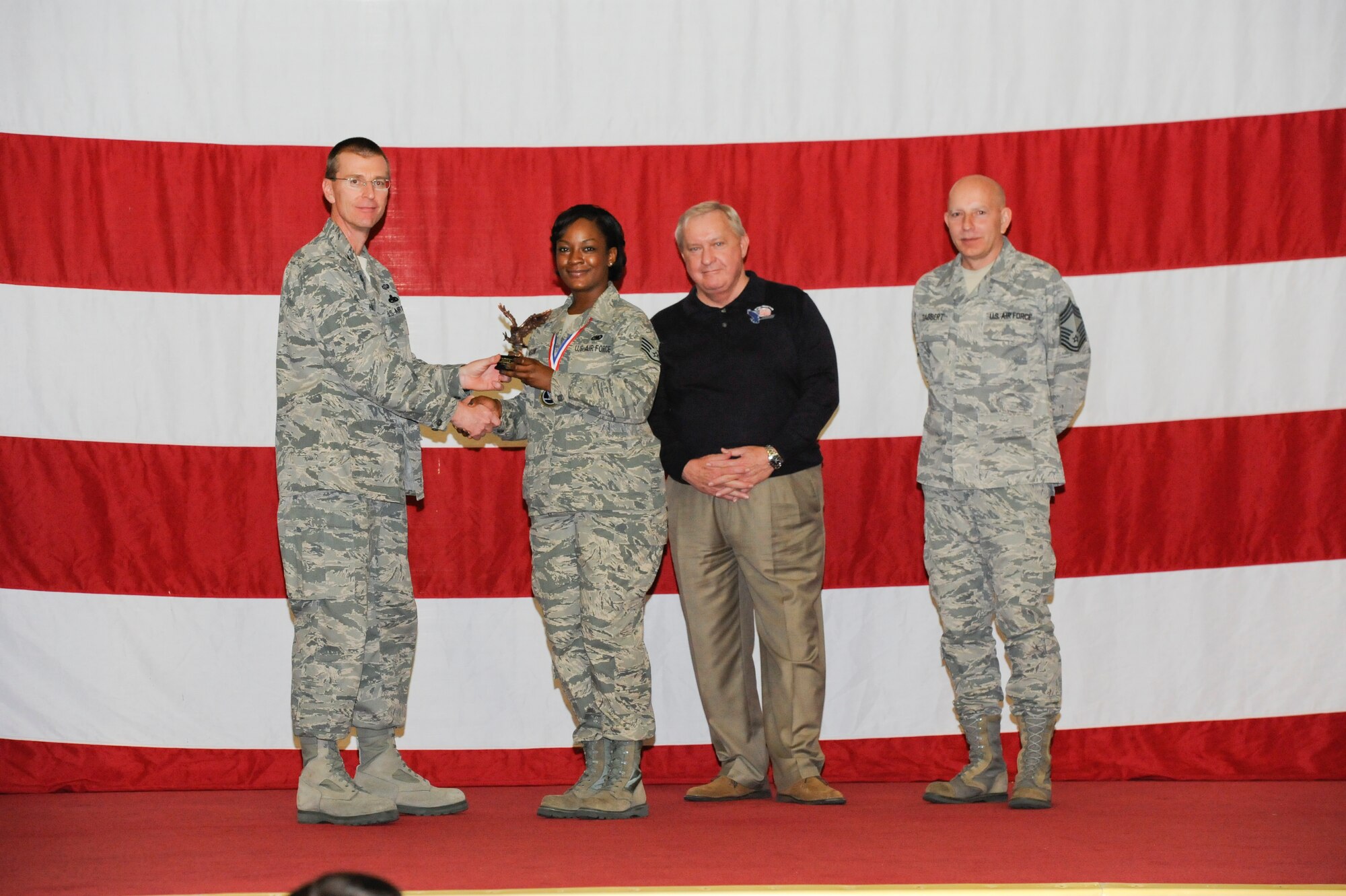 Staff Sgt. Christina Johnson, 325th Aircraft Maintenance Squadron, receives the award for the Outstanding Supply Person of the Year from Col. Curtis Hafer, 325th Maintenance Group commander, and Chief Master Sgt. Terry Gabbert, 325th MXG superintendent, and retired ninth Chief Master Sergeant of the Air Force, Chief Master Sgt. James Binnicker, during the 2012 Maintenance and Staff Professionals of the Year banquet in Hangar 1 March 15. The MPOY banquet recognizes the achievements of the maintenance group and honors maintenance professionals each year. (U.S. Air Force photo by Chris Cokeing)