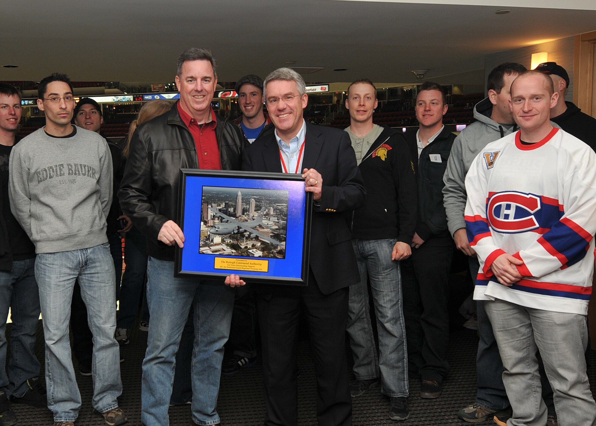 RALEIGH, N.C.  –   Lt. Col. Timothy Moran shows appreciation to The Centennial Authority of Raleigh on behave of 145th Civil Engineering Squadron and Royal Air Force 3 Wing Construction Engineers Canadian Forces from Bagotville, Quebec, by presenting a photo of a 145th Airlift Wing, C-130 Hercules aircraft to Jeff Merritt during Hurricane vs. Montréal Canadians NHL game on March 7, 2013. Canadian engineers participated in a two week Deployment for Training Program, an exchange agreement between the Royal Canadian Air Force and the United States Air National Guard held at the North Carolina Air National Guard Regional Training Site in New London, N.C.  (National Guard Photo by Tech. Sgt. Patricia Findley, 145th Public Affairs) 