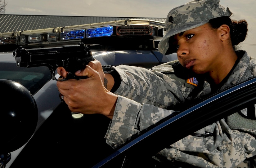 U.S. Army Spc. Adrianna Williamson, 221st Military Police Detachment patrolman, demonstrates how patrolmen use their vehicle for cover should they have to draw their weapon at Fort Eustis, Va., March 20, 2013. March marks the time to reflect on the struggles and triumphs women have gone through as part of Women’s History Month. (U.S. Air Force photo by Staff Sgt. Wesley Farnsworth/Released)