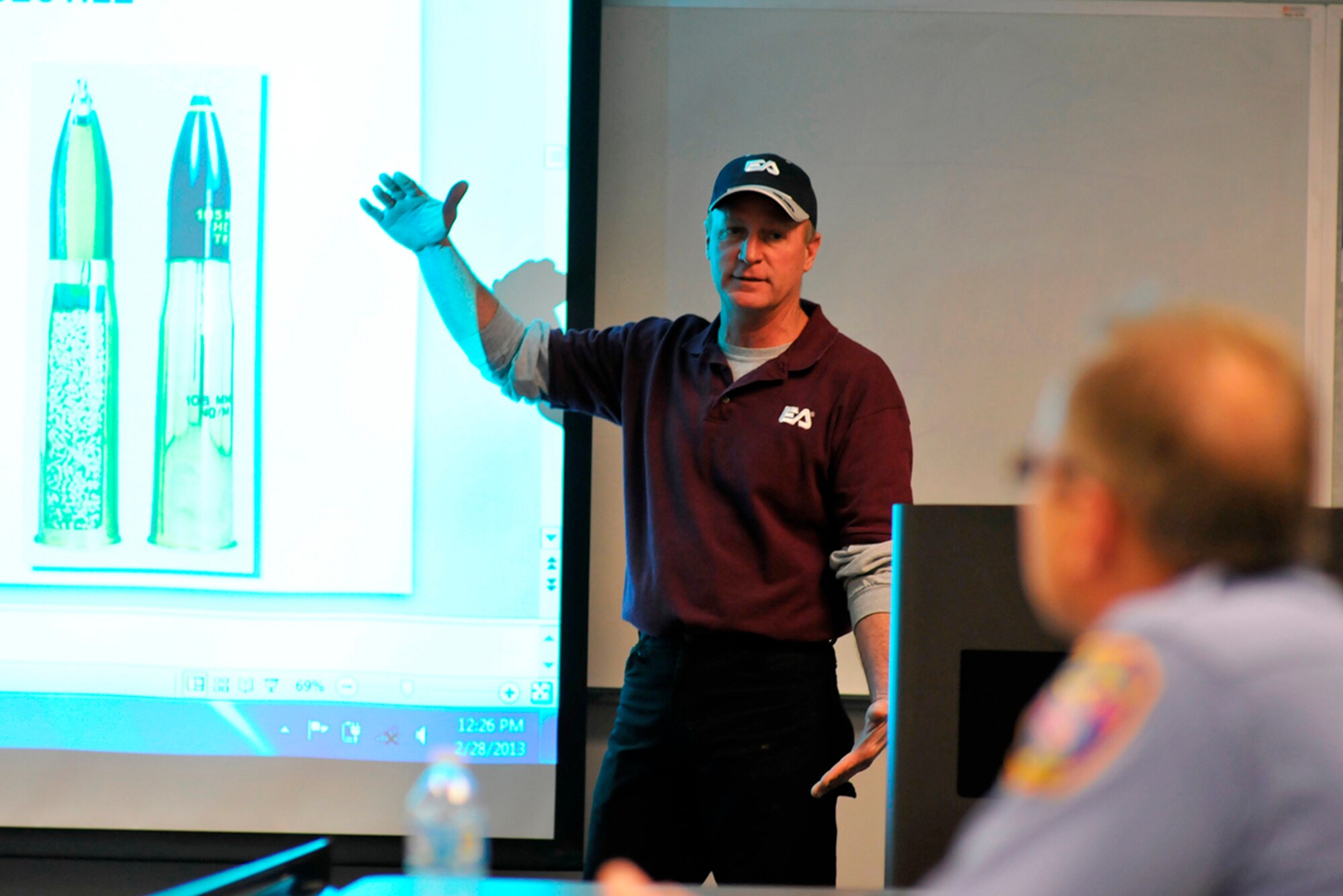 Addressing a class of AEDC firefighters and police security officers, Jim Miller, the UXO safety officer for EA Engineering, Corp., uses his arms to demonstrate the size of a 105 millimeter Howitzer round that can be found in certain areas [formerly Camp Forrest munitions ranges] of Arnold Air Force Base. (Photo by Rick Goodfriend)