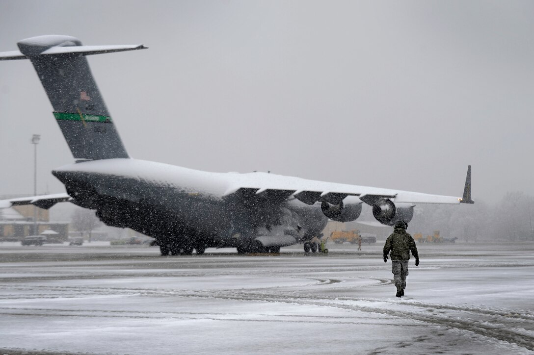 A staff sergeant walks towards a C-17 Globemaster III aircraft on the flightline at Joint Base Andrews, Md., March 25, 2013, during a spring snowstorm. (U.S. Air Force photo/Staff Sgt. Brittany E. Jones)