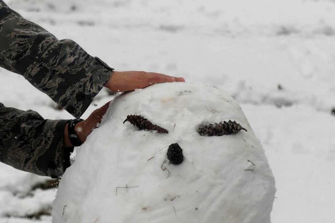 Senior Airman Edwin Santos Limon, Joint Base Andrews Honor Guard, take a break to build a snowman, March 25, 2013 at Joint Base Andrews, Md. The spring snowstorm is forecasted to bring up to five inches of snow to the local area.  (U.S. Air Force photo/Staff Sgt. Brittany E. Jones)