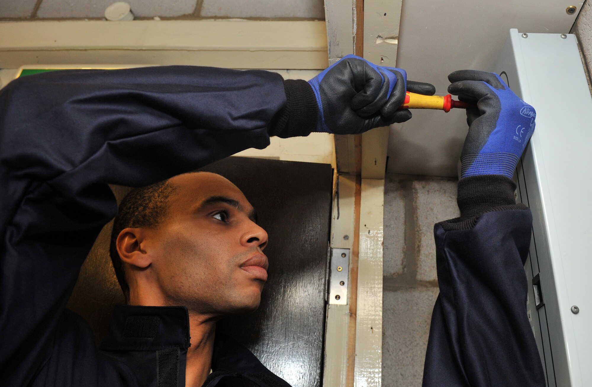 Tech. Sgt. Dramel Jackson, 100th Civil Engineer Squadron electrician from New Haven, Conn., removes the screws from an electrical panel March 22, 2013, at RAF Mildenhall, England. The electrical shop is comprised of both Airmen and Civilians responsible for all interior electrical systems on base as well as on the airfield. (U.S. Air Force photo by Senior Airman Jerilyn Quintanilla/Released)