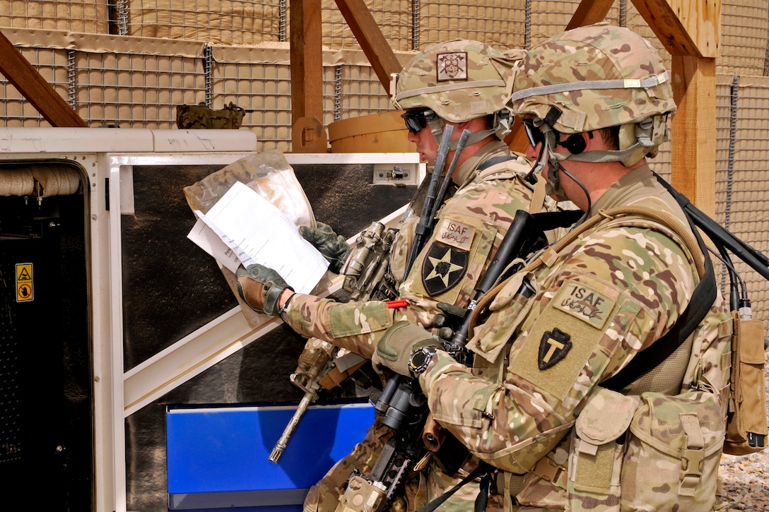 U.S. Army 1st Lt. Darren C. Bliler, left, and U.S. Army Sgt. David A. Hixon, right, look over manuals to help Afghan uniformed police fix their generator at a checkpoint during a visit by International Security Assistance Forces in the Spin Boldak district of Afghanistan’s Kandahar province, March 19, 2013. Darren is assigned to the 2nd Infantry Division's Company B, 2nd Battalion, 23rd Infantry Regiment, 4th Striker Brigade Combat Team, and Hixon is assigned to the Security Force Assistance Team 20.