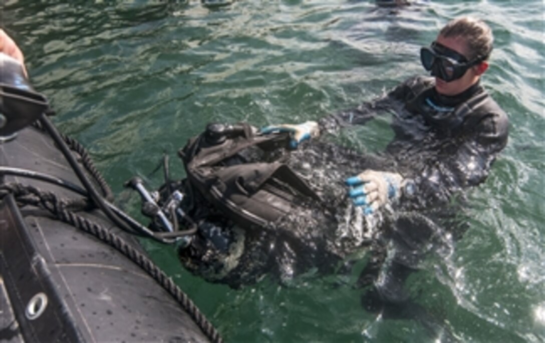 U.S. Navy Petty Officer 2nd Class Holly Ramirez checks her dive gear before a dive for structural pile restoration at the Hotel piers on Joint Base Pearl Harbor-Hickam on March 20, 2013.  Ramirez is attached to Construction Dive Detachment Alpha, part of Underwater Construction Team 2 of Port Hueneme, Calif.  The team provides a capability for construction, inspection, repair, and maintenance of ocean facilities in support of Naval and Marine Corps operations.  