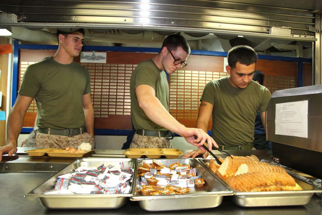 From left to right: Lance Cpl. Victor Hillmann, machine gunner, Combined Anti-Armor Team 1, Weapons Company, Battalion Landing Team 3/5, 15th Marine Expeditionary Unit, Cpl. Brandon Biggerstaff, landing support specialist, Transportation Support Detachment, Combat Logistics Battalion 15, 15th MEU, and Lance Cpl. Raphael Ibarra, landing support specialist, TS Detachment, CLB-15, 15th MEU, serve themselves dinner while on mess duty aboard USS Rushmore, March 15. The 15th MEU is deployed as part of the Peleliu Amphibious Ready Group as a U.S. Central Command theater reserve force, providing support for maritime security operations and theater security cooperation efforts in the U.S. 5th Fleet area of responsibility. (U.S. Marine Corps photo by Cpl. Timothy R. Childers/Released)