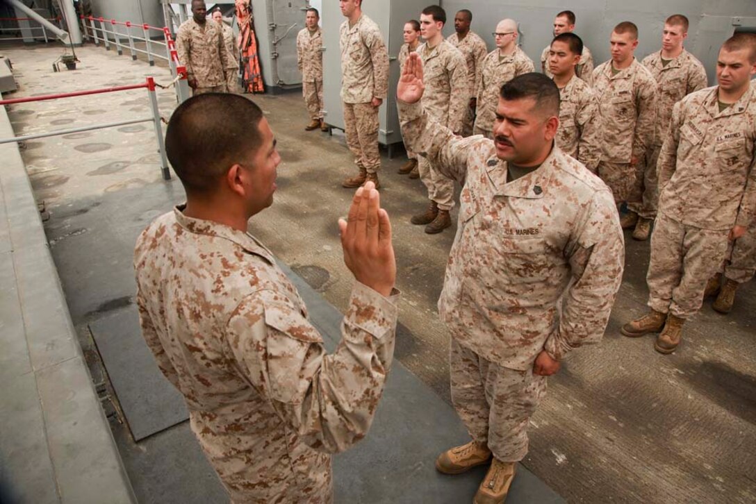Gunnery Sgt. Raul O. Chapa (right), radio chief, Command Element, 15th Marine Expeditionary Unit, re-enlists under the authority of 1st Lt. Alfonso Cortes, officer-in-charge, Joint Task Force Enabler, on USS Peleliu, March 20. Chapa, 34, is from San Antonio, Texas, and joined the Marine Corps for a challenge to be a part of the best. He chose communications because it enabled him to be close to the infantry, and he was interested in the technology aspect. To pass the time on deployment, he enjoys going to the gym daily and spending time with his Marines. His favorite part of the deployment has been serving with the Command Element because it allowed him to gain a new perspective of the Marine Air-Ground Task Force. He is looking forward to spending time with his family the most when he returns home. The 15th MEU is deployed as part of the Peleliu Amphibious Ready Group as a U.S. Central Command theater reserve force, providing support for maritime security operations and theater security cooperation efforts in the U.S. 5th Fleet area of responsibility. (U.S. Marine Corps photo by Cpl. John Robbart III/Released)