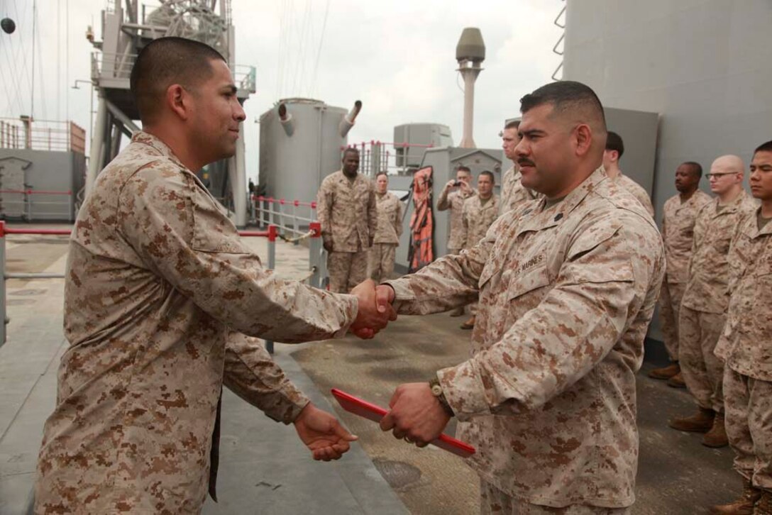 Gunnery Sgt. Raul O. Chapa (right), radio chief, Command Element, 15th Marine Expeditionary Unit, receives his Certificate of Re-enlistment and shakes hands with 1st Lt. Alfonso Cortes, officer-in-charge, Joint Task Force Enabler, after re-enlisting on USS Peleliu, March 20. Chapa, 34, is from San Antonio, Texas, and joined the Marine Corps for a challenge to be a part of the best. He chose communications because it enabled him to be close to the infantry, and he was interested in the technology aspect. To pass the time on deployment, he enjoys going to the gym daily and spending time with his Marines. His favorite part of the deployment has been serving with the Command Element because it allowed him to gain a new perspective of the Marine Air-Ground Task Force. He is looking forward to spending time with his family the most when he returns home. The 15th MEU is deployed as part of the Peleliu Amphibious Ready Group as a U.S. Central Command theater reserve force, providing support for maritime security operations and theater security cooperation efforts in the U.S. 5th Fleet area of responsibility. (U.S. Marine Corps photo by Cpl. John Robbart III/Released)
