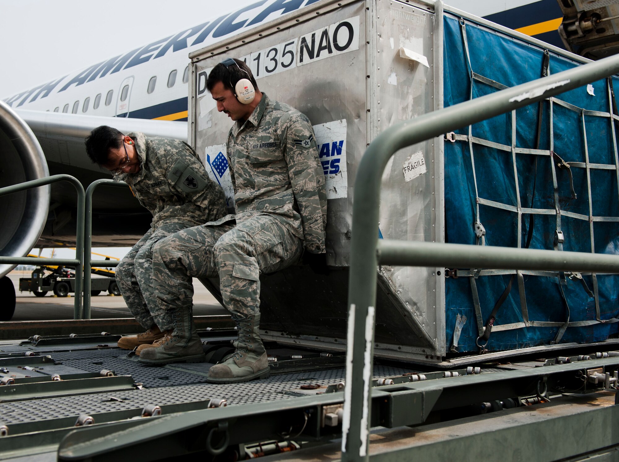 YOKOTA AIR BASE, Japan -- Airman 1st Class Grayson Glass and Army Sgt. Paulus Hindarto from the 623rd Movement Control Team, 35th Combat Sustainment Support Battalion, retrieve cargo from an aircraft at Yokota Air Base, Japan, March 20, 2013. Soldiers from the 623rd Movement Control Team deal with the loading and unloading of cargo everyday in their career field, and their visit to Yokota allowed them to familiarize themselves with possible Air Force assets they will encounter while moving cargo in a deployed location.  (U.S. Air Force photo by Airman 1st Class Meagan Schutter)