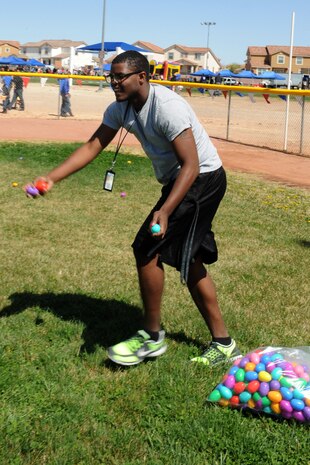 Treyvon James, a member of the University of Nevada Las Vegas football team, tosses plastic Easter eggs during the Nellis Air Force Base, Nev., Easter egg hunt and extravaganza March 23, 2013, at the Nellis Youth Center sports field. The day included multiple egg hunts for children ages 1 to12, games, prizes and music. (U.S. Air Force photo by Tech. Sgt. Taylor Worley)  