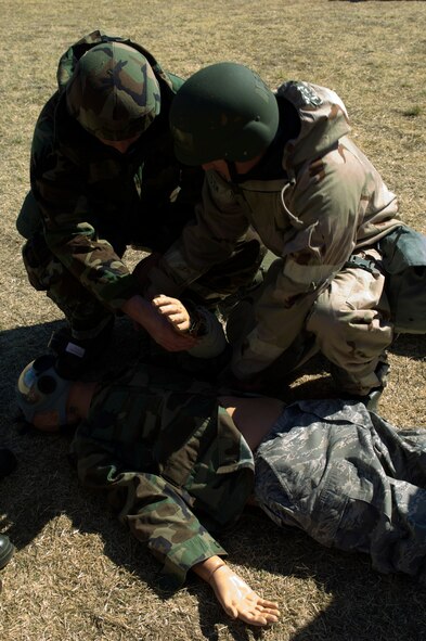 Maj. Dan Kunkel, 28th Bomb Squadron, left, and Senior Airman Mark Moser, 7th Aircraft Maintenance Squadron, right, apply a tourniquet to a training aid during ability-to-survive and operate training March 26, 2013, at Dyess Air Force Base, Texas. Airmen across the 7th Bomb Wing simulated many scenarios that consisted of self-aid and buddy care and chemical, biological, radioactive, nuclear explosive responses in preparation for the wing’s upcoming operational readiness exercise. (U.S. Air Force photo by Airman 1st Class Kylsee Wisseman/ Released) 