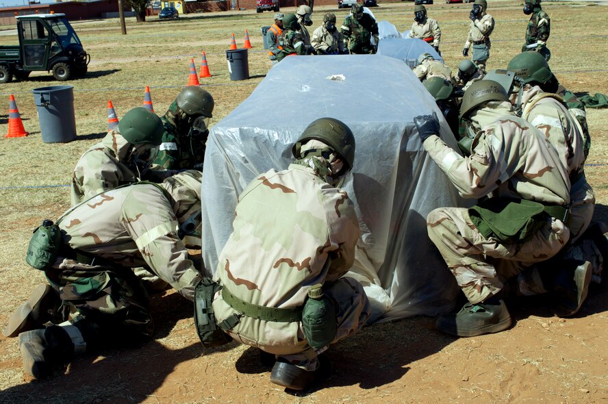 Dyess Airmen practice covering vehicle assets during ability-to-survive and operate training March 26, 2013, at Dyess Air Force Base, Texas. Airmen across the 7th Bomb Wing simulated many scenarios that consisted of self-aid and buddy care and chemical, biological, radioactive, nuclear explosive responses in preparation for the wing’s upcoming operational readiness exercise. (U.S. Air Force photo by Airman 1st Class Kylsee Wisseman/ Released) 