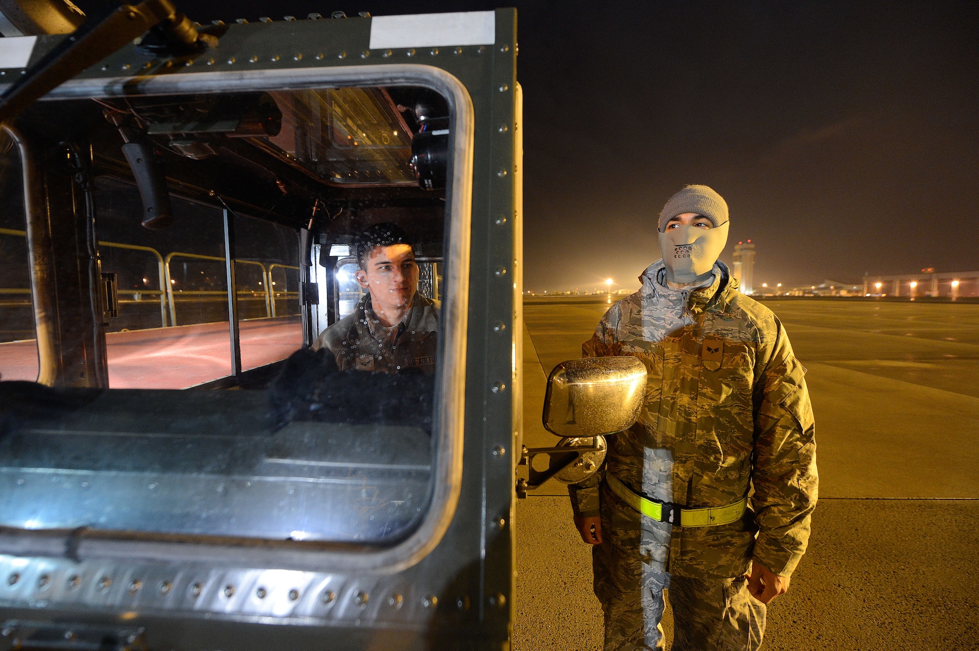 Airman 1st Class Calob Hayes enjoys the relative warmth inside the cab of a K-loader while Senior Airman Alex Delgado stands in the cold weather during the early morning hours, March 26, 2013, Dover Air Force Base, Del. Both airmen are from the 436th Aerial Port Squadron and are waiting to move in to position to unload cargo arriving from overseas. Airmen from the 436th APS operate Dover's Aerial Port, the largest and busiest air freight terminal in the Department of Defense. (U.S. Air Force photo/Greg L. Davis)
